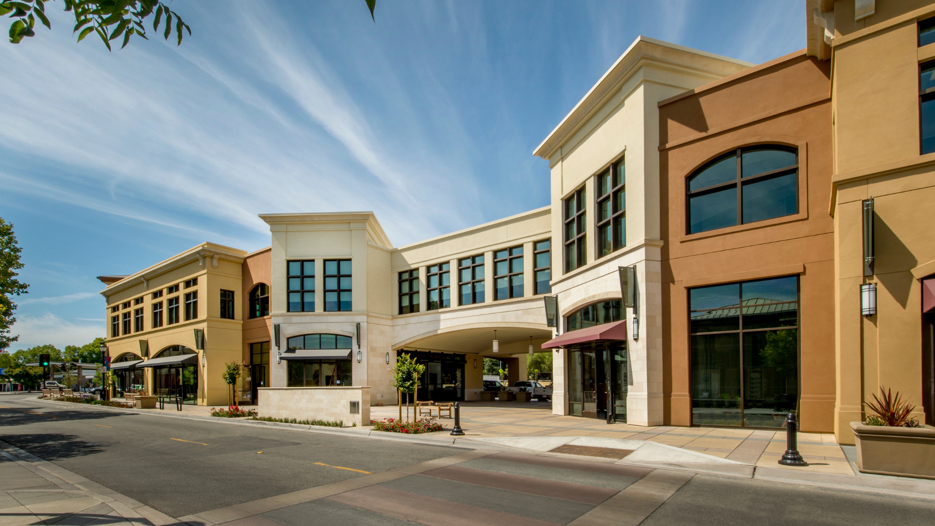 Row of modern storefronts along a sunny street with beige and tan facades under a blue sky