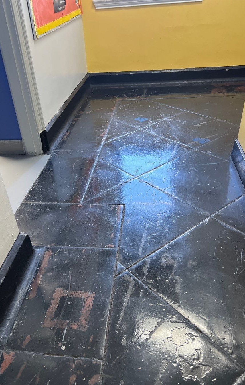 Black floor with geometric patterns and water. Reflections in a hallway.