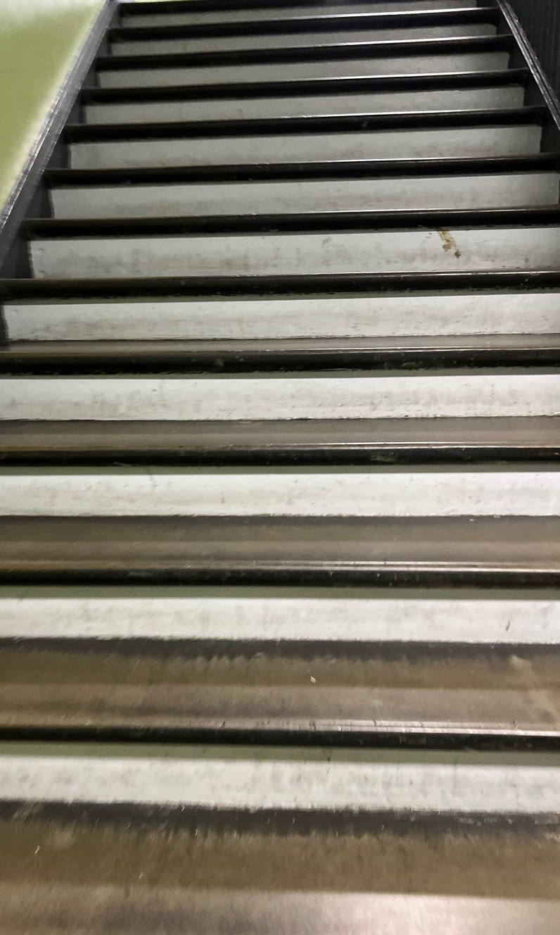 Staircase with white treads and black edges, viewed from the bottom looking upwards, in a building.