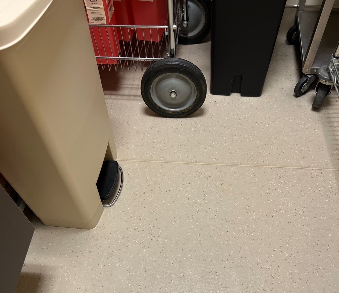 Beige floor with storage bins, a cart, and wheels in an indoor space.