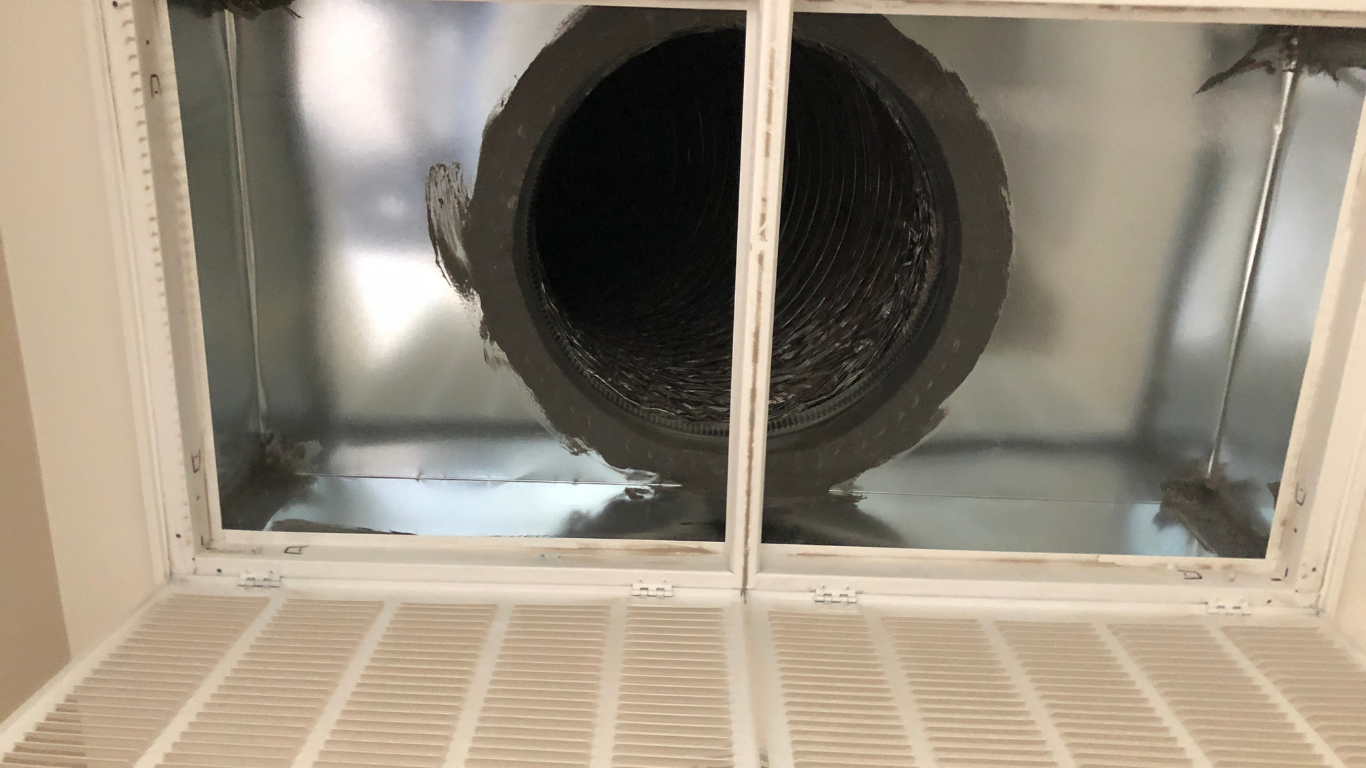 View up into a ceiling vent with a large black circular duct in a metal HVAC opening