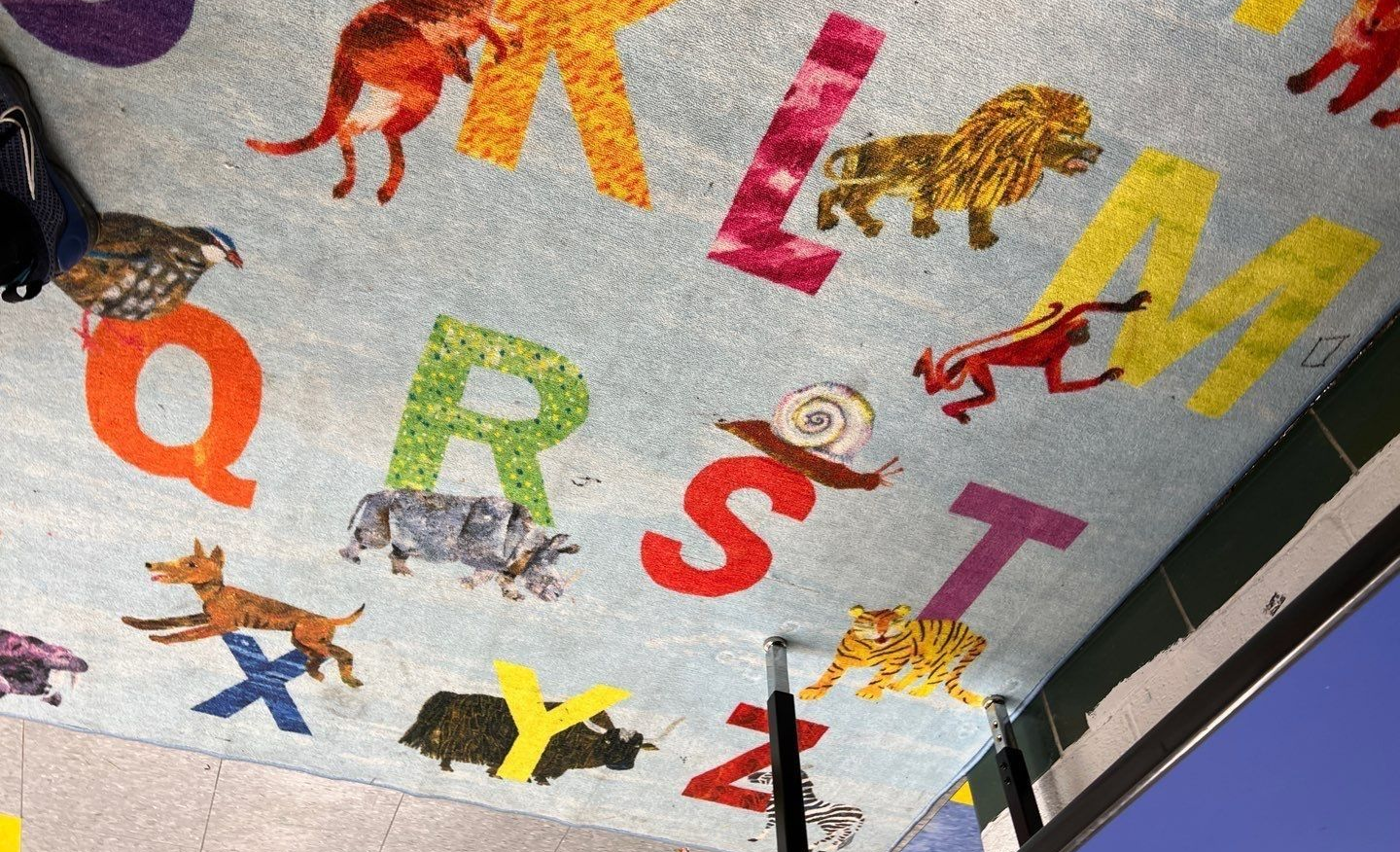 Colorful alphabet rug with animal illustrations, including a lion, dog, and fox.