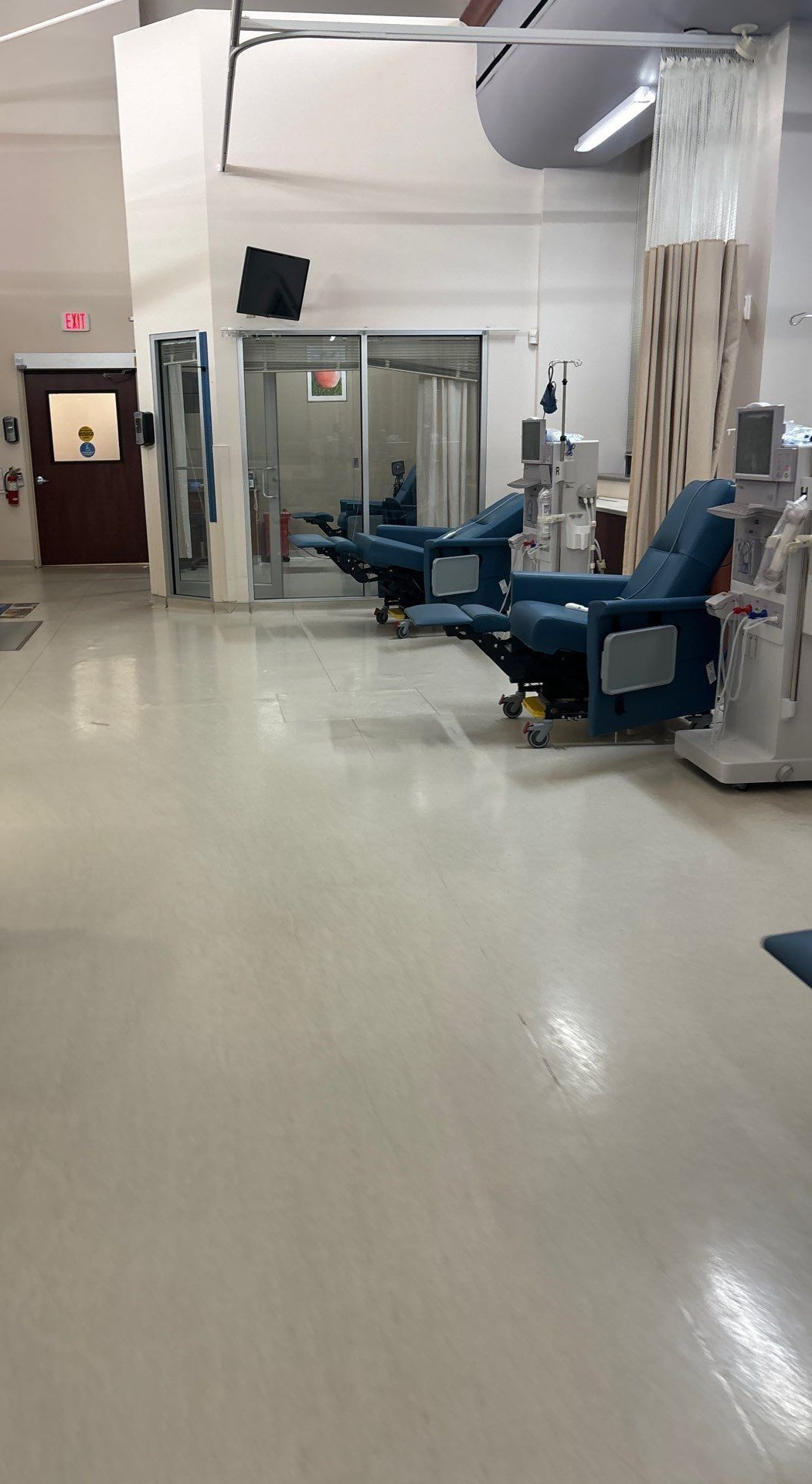Interior of a medical facility with recliners, medical equipment, and curtained areas.