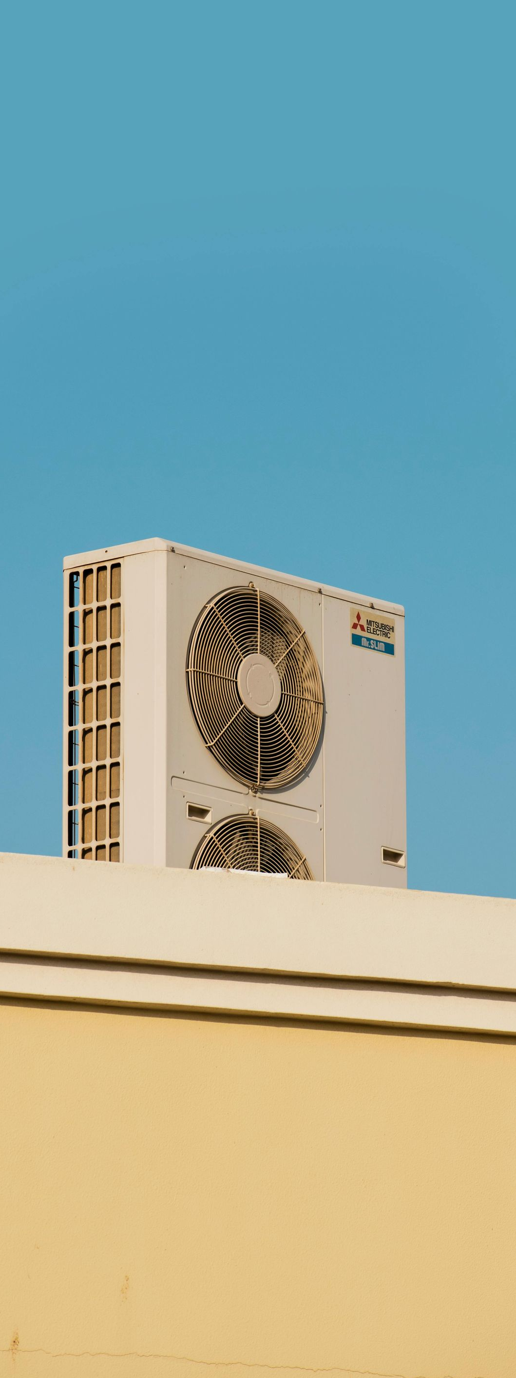 Air conditioner unit mounted on a beige rooftop against a blue sky