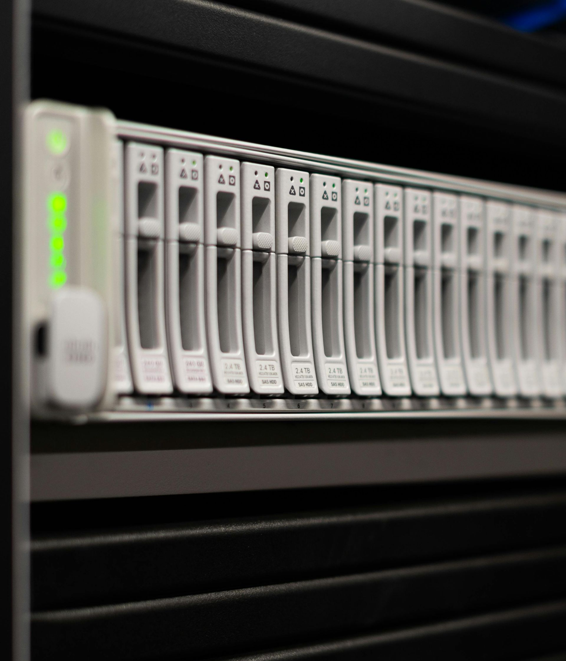 A rack-mounted server with a row of silver hard drive bays, one displaying a bright green status light.
