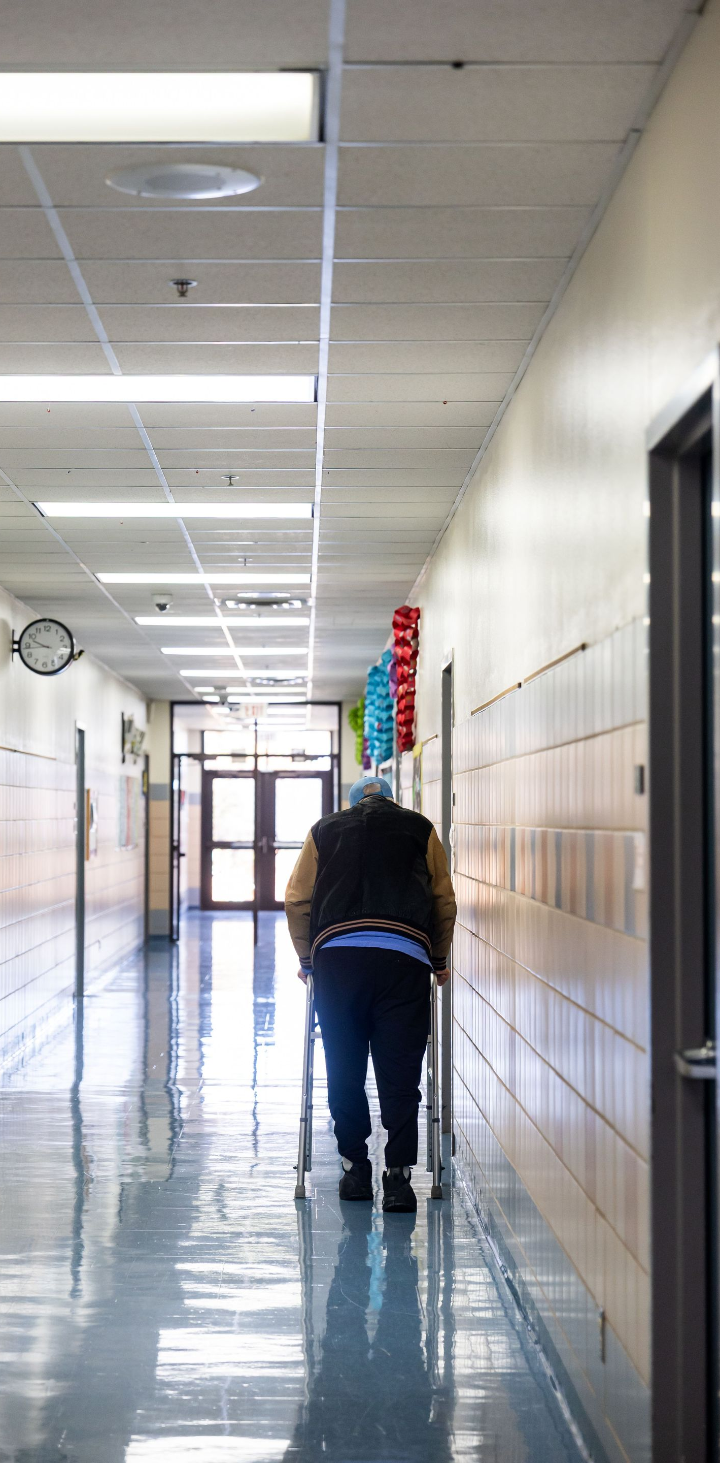 Person mopping a shiny school hallway with lockers along the wall