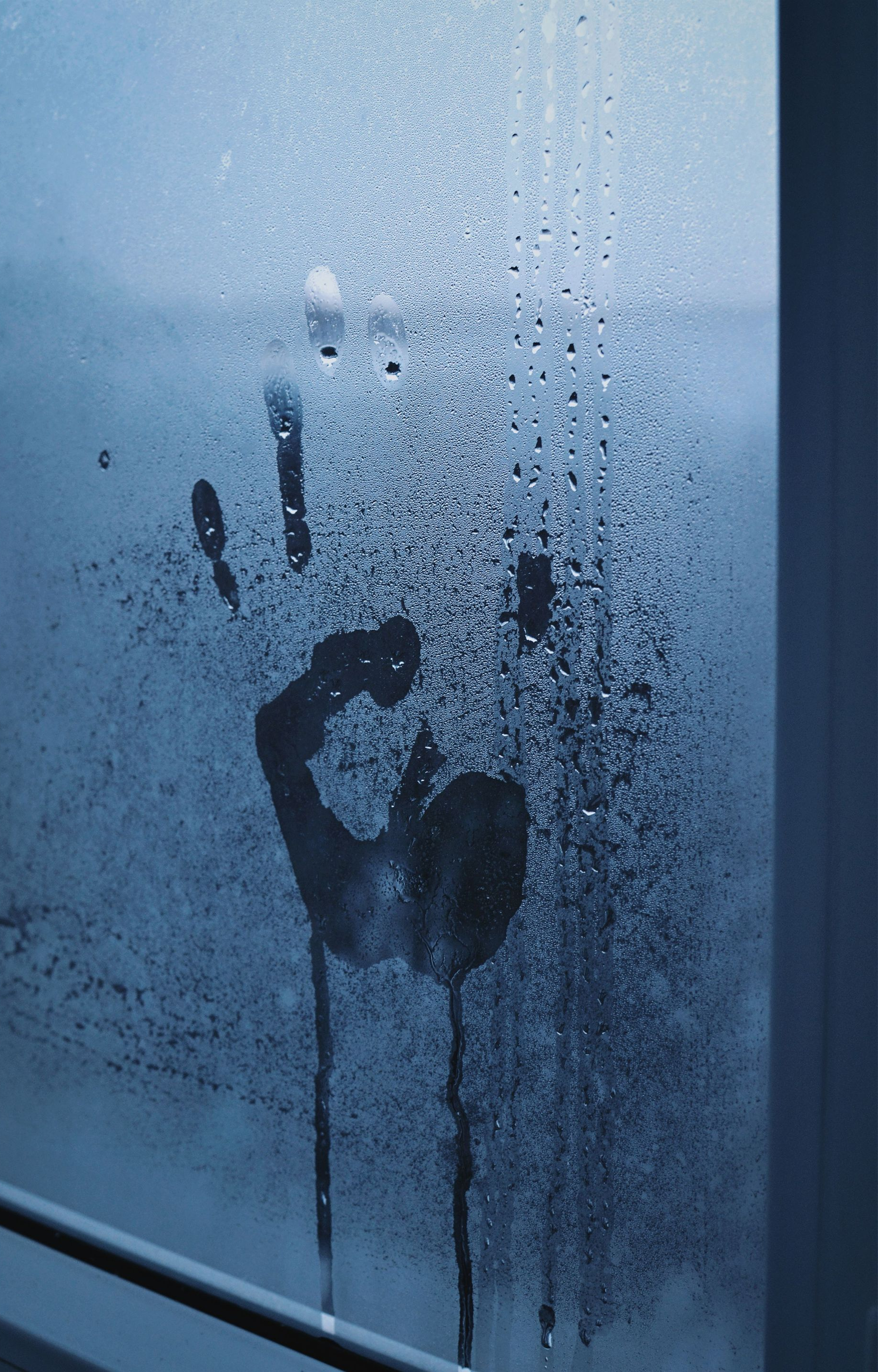 Handprint and streaks on a fogged blue window