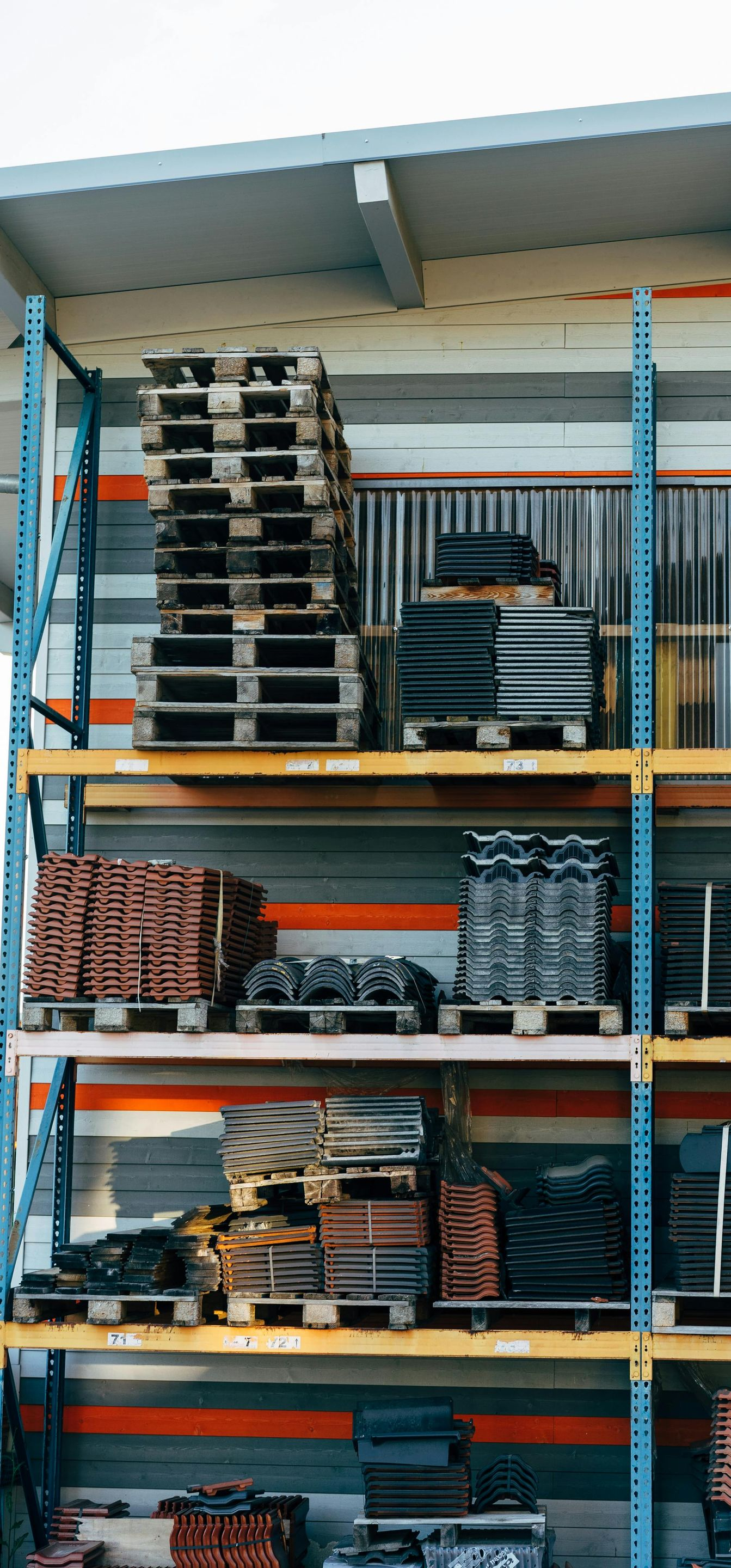 Shelving units stocked with folded clothing and fabric bolts in a store warehouse