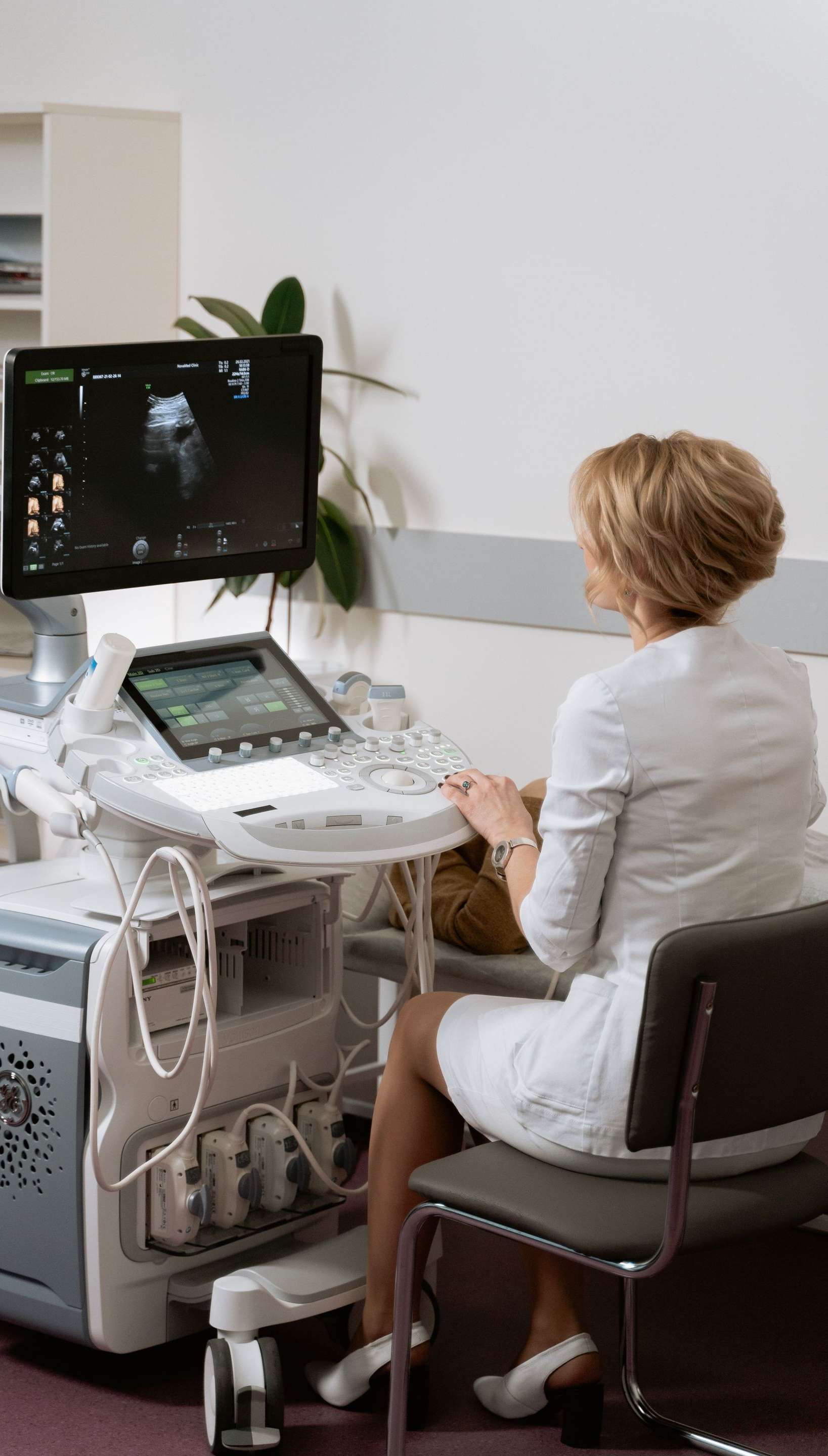 Medical professional seated at an ultrasound machine, viewing a patient scan on a monitor