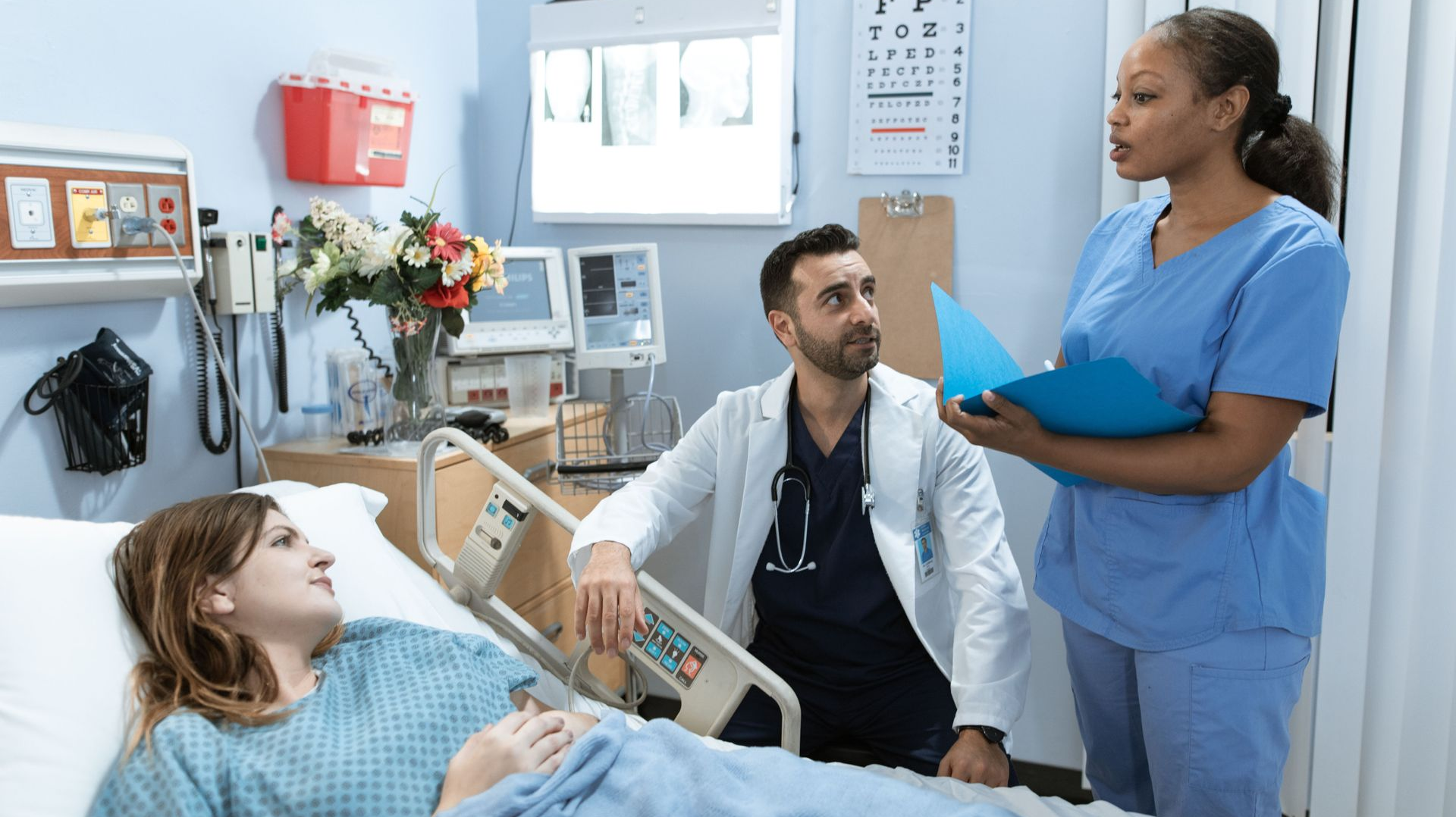 Hospital room with a doctor and nurse talking to a patient in bed