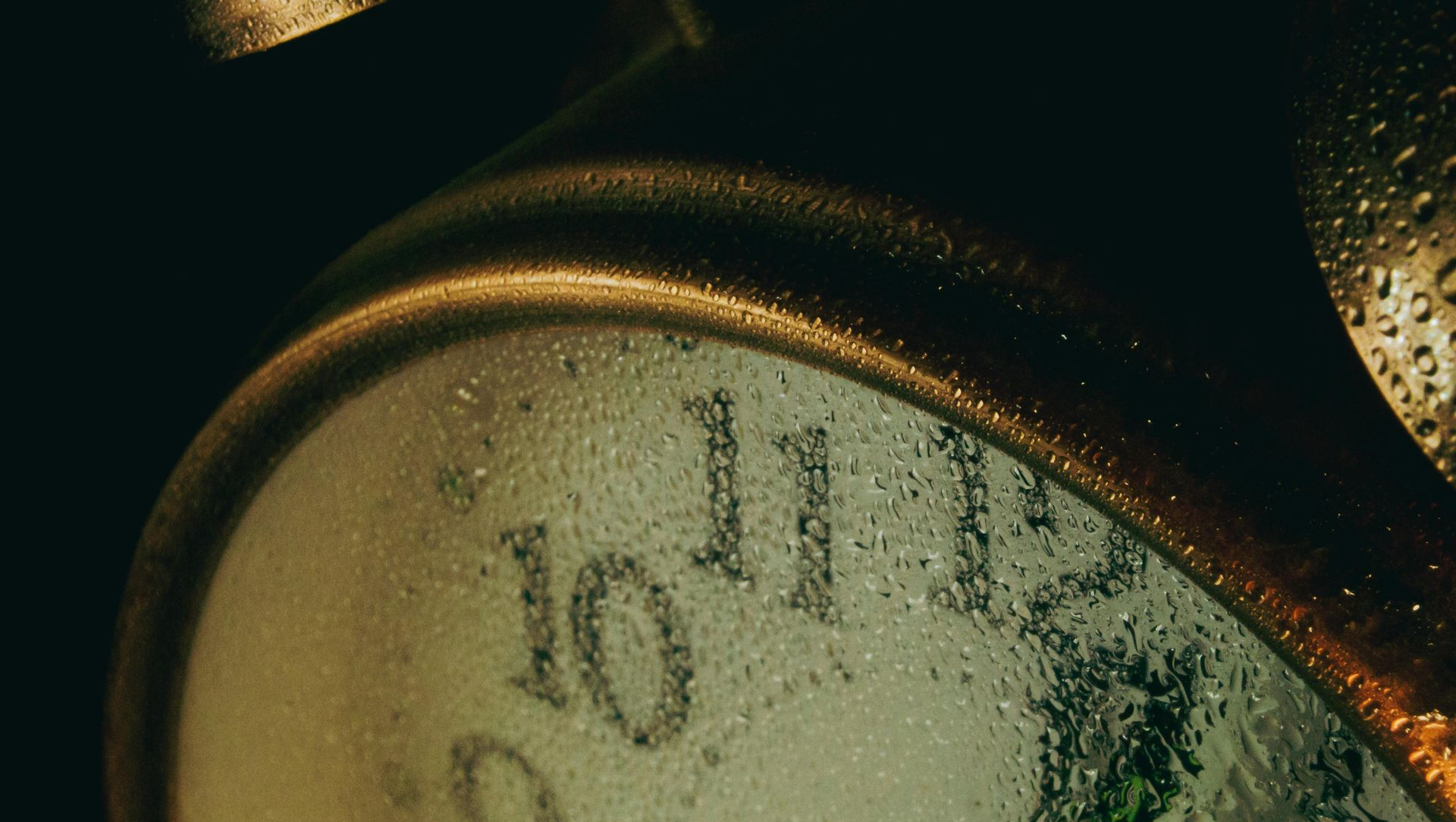 Close-up of a vintage clock face with Roman numerals in warm, dim light