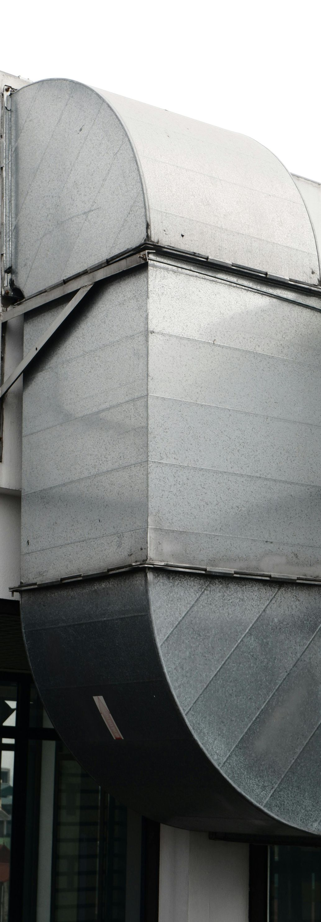 Gray metal ductwork and venting on a building exterior.