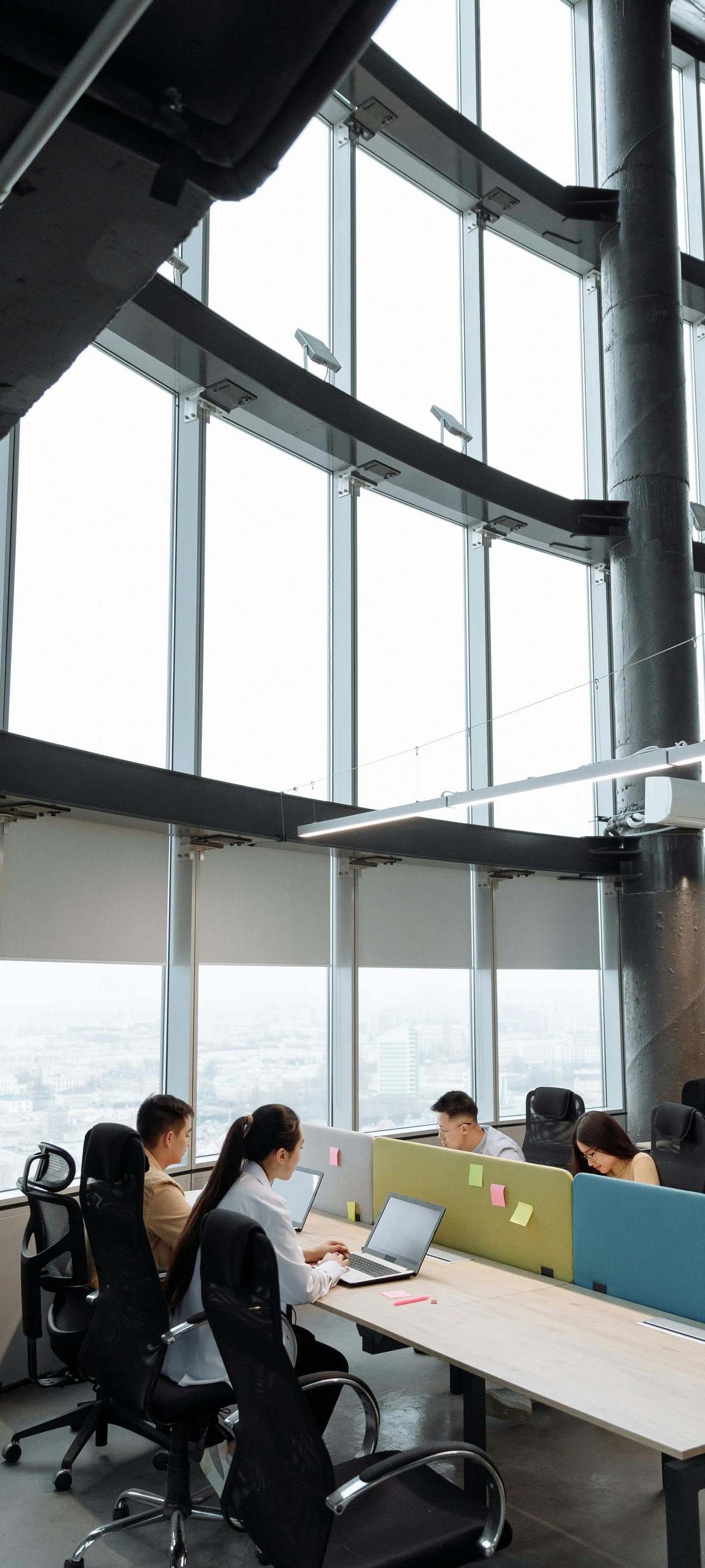 People working at desks in a modern glass-walled office with city views