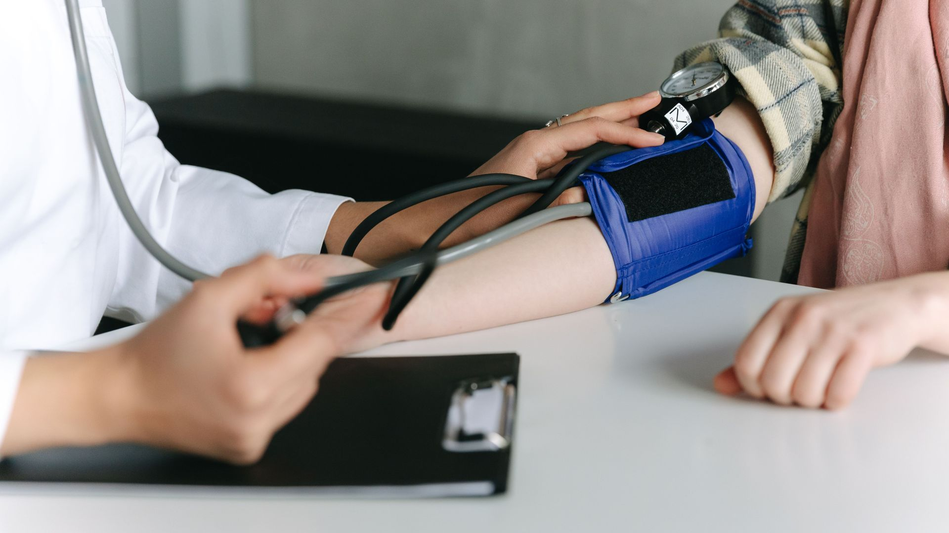 Blood pressure being measured with a cuff on a person’s arm at a table