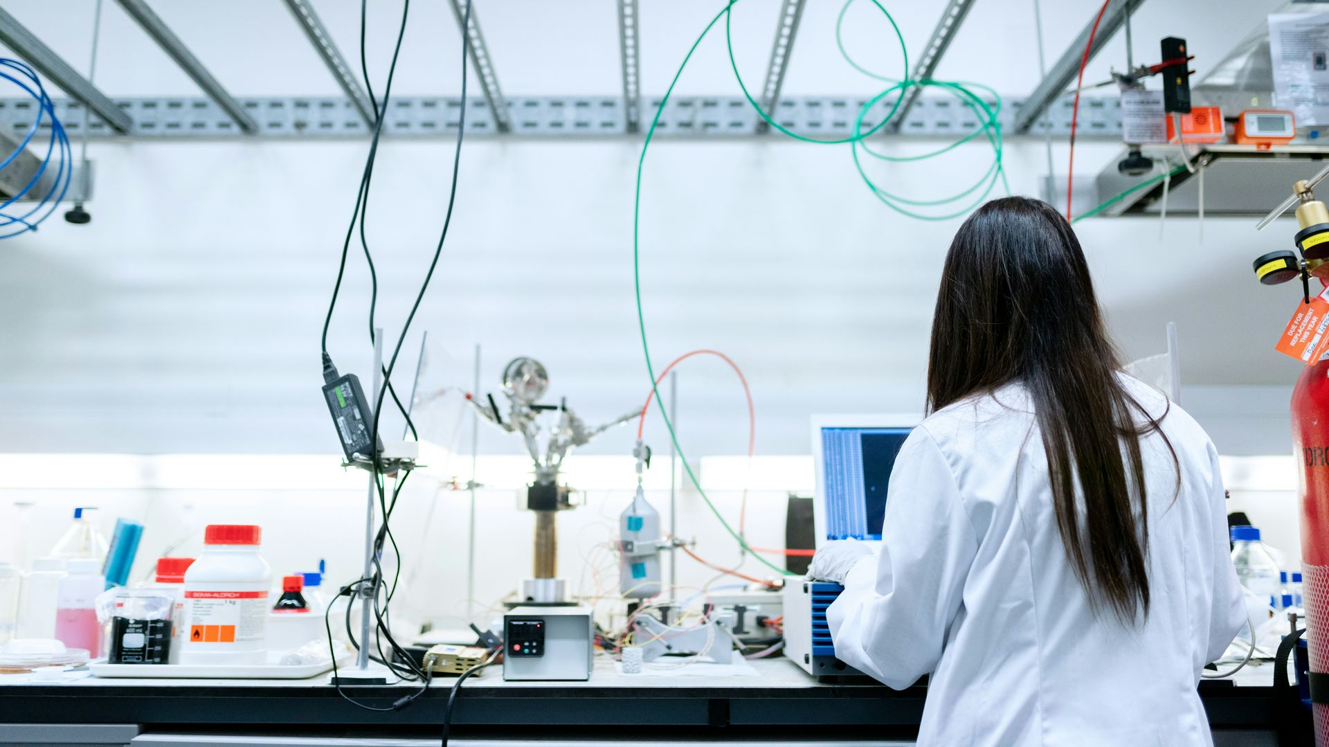 Scientist working at a lab bench with wiring and equipment in a bright research lab