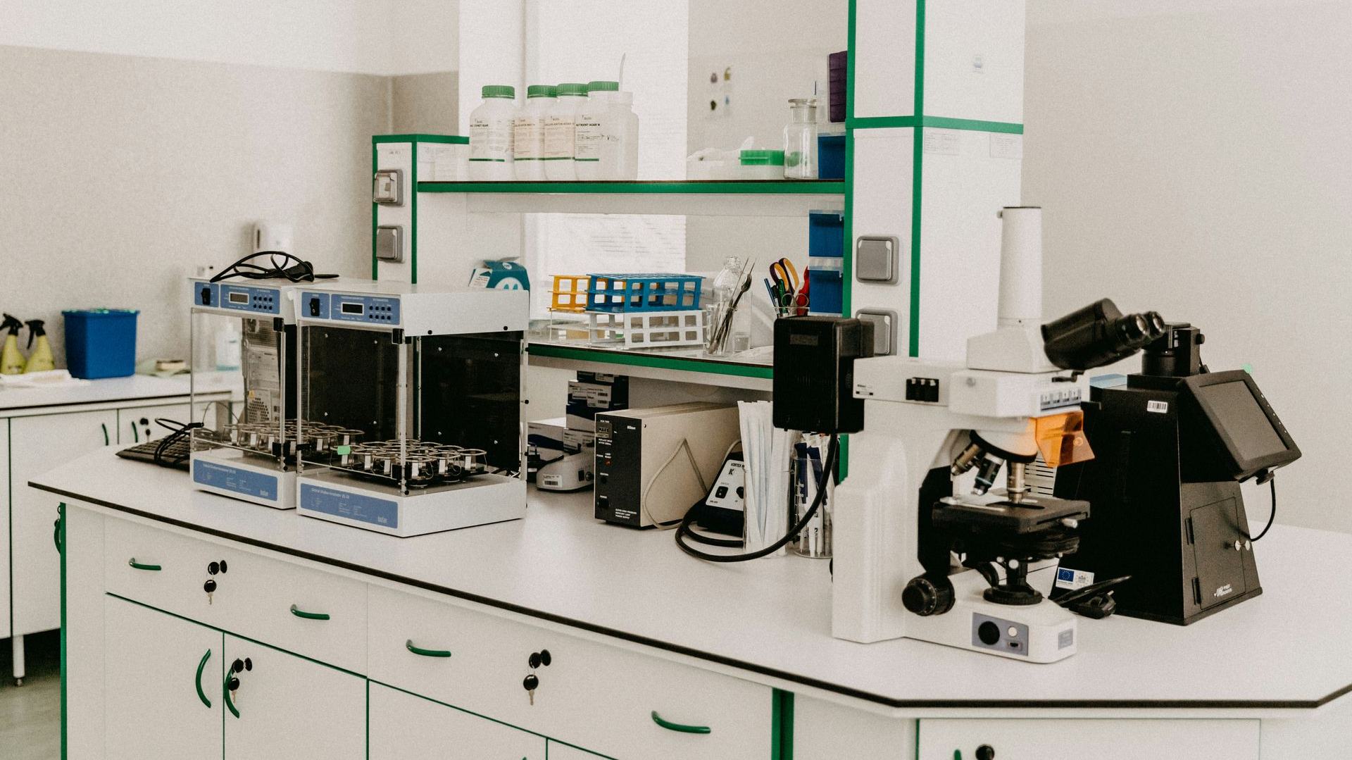 Laboratory bench with microscopes and testing equipment in a clean, white lab.