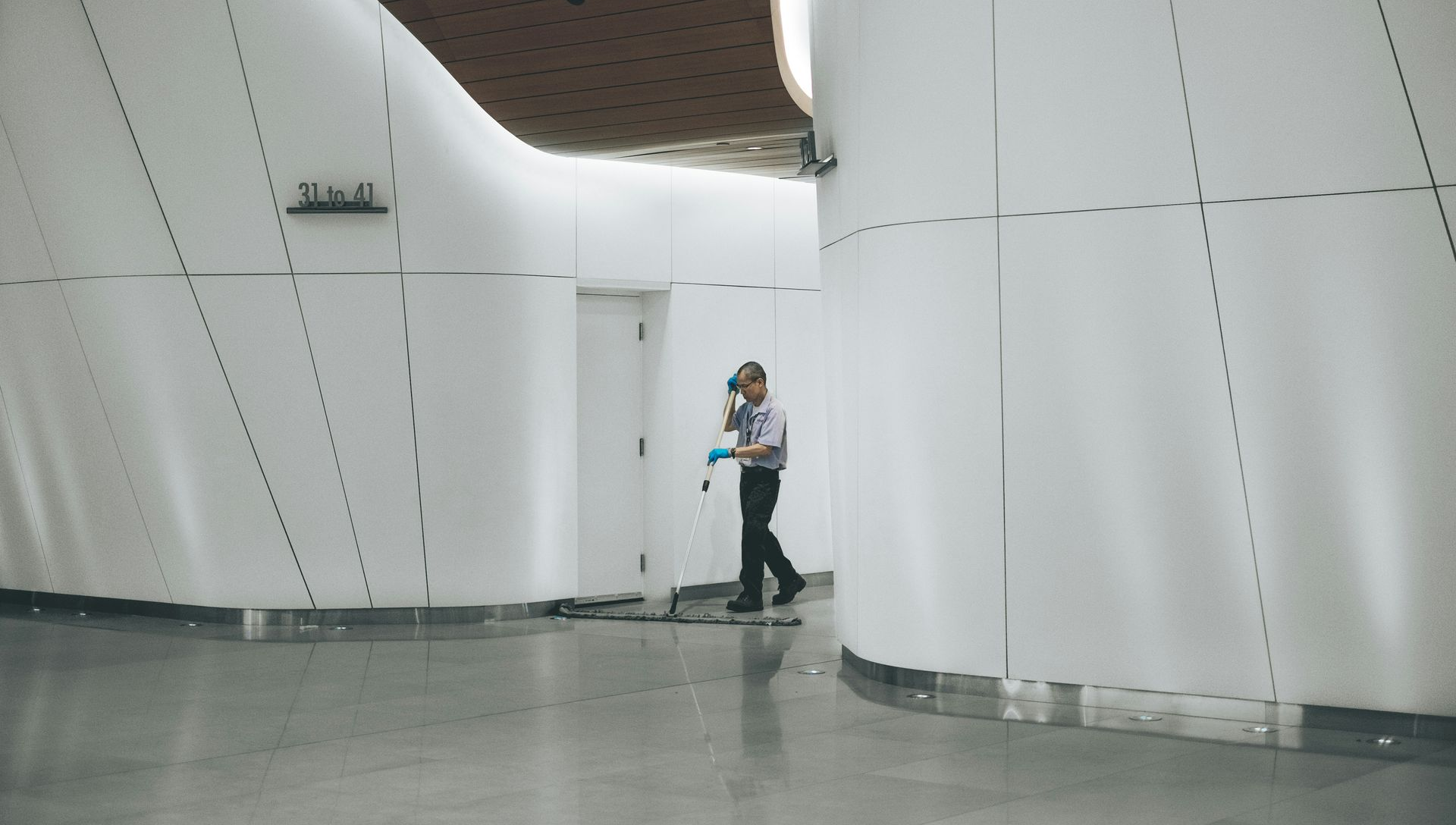 Person walking through a modern, white-walled corridor.
