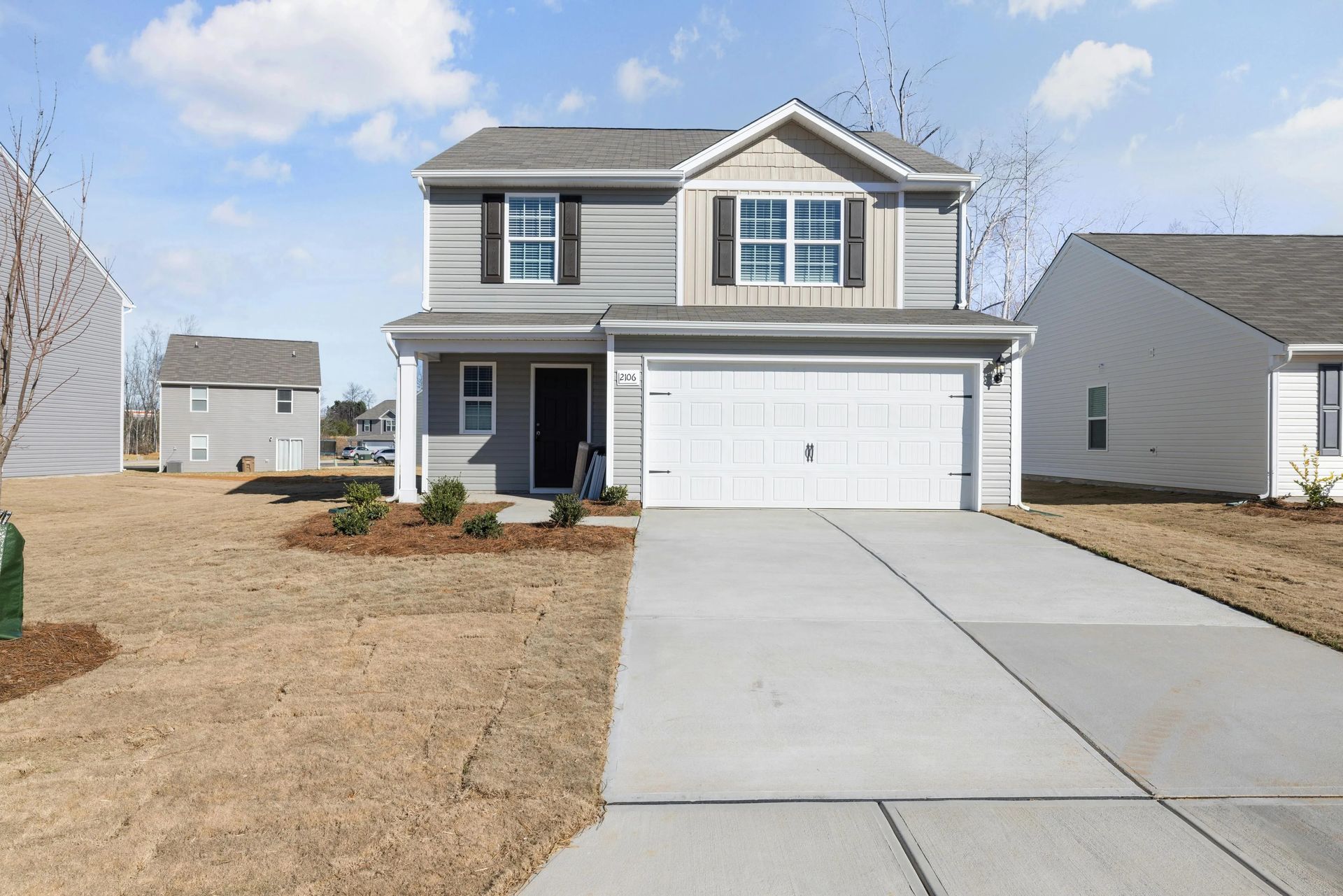 Two-story gray suburban house with a double garage and a concrete driveway in a new development
