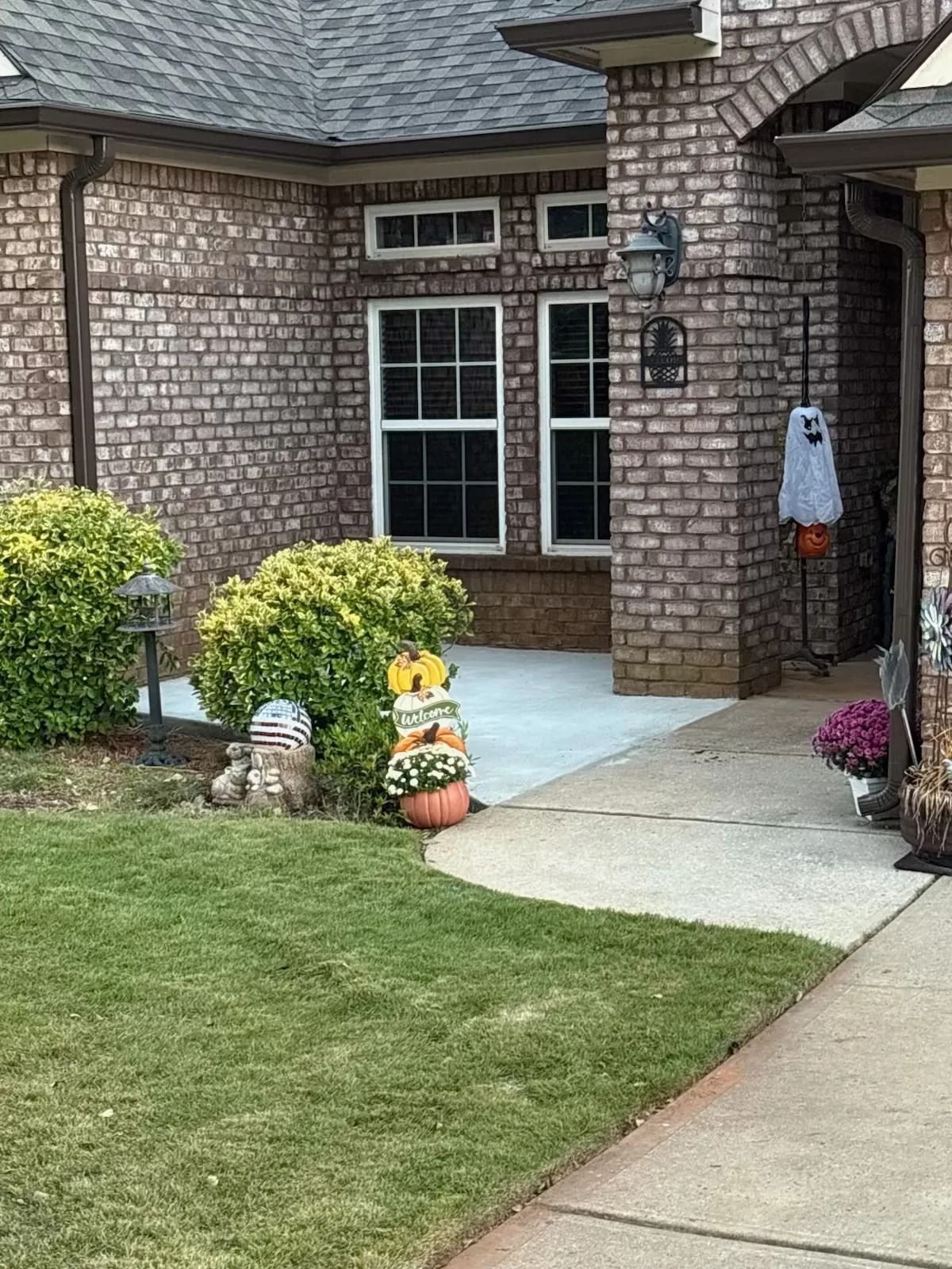 Brick house front entry with windows, potted flowers, lawn, and walkway