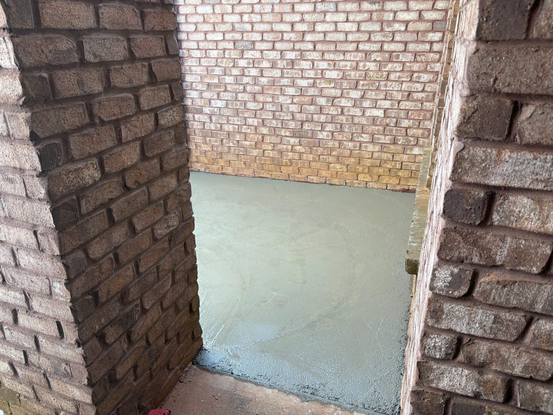 Unfinished brick interior with fresh concrete floor and exposed brick walls
