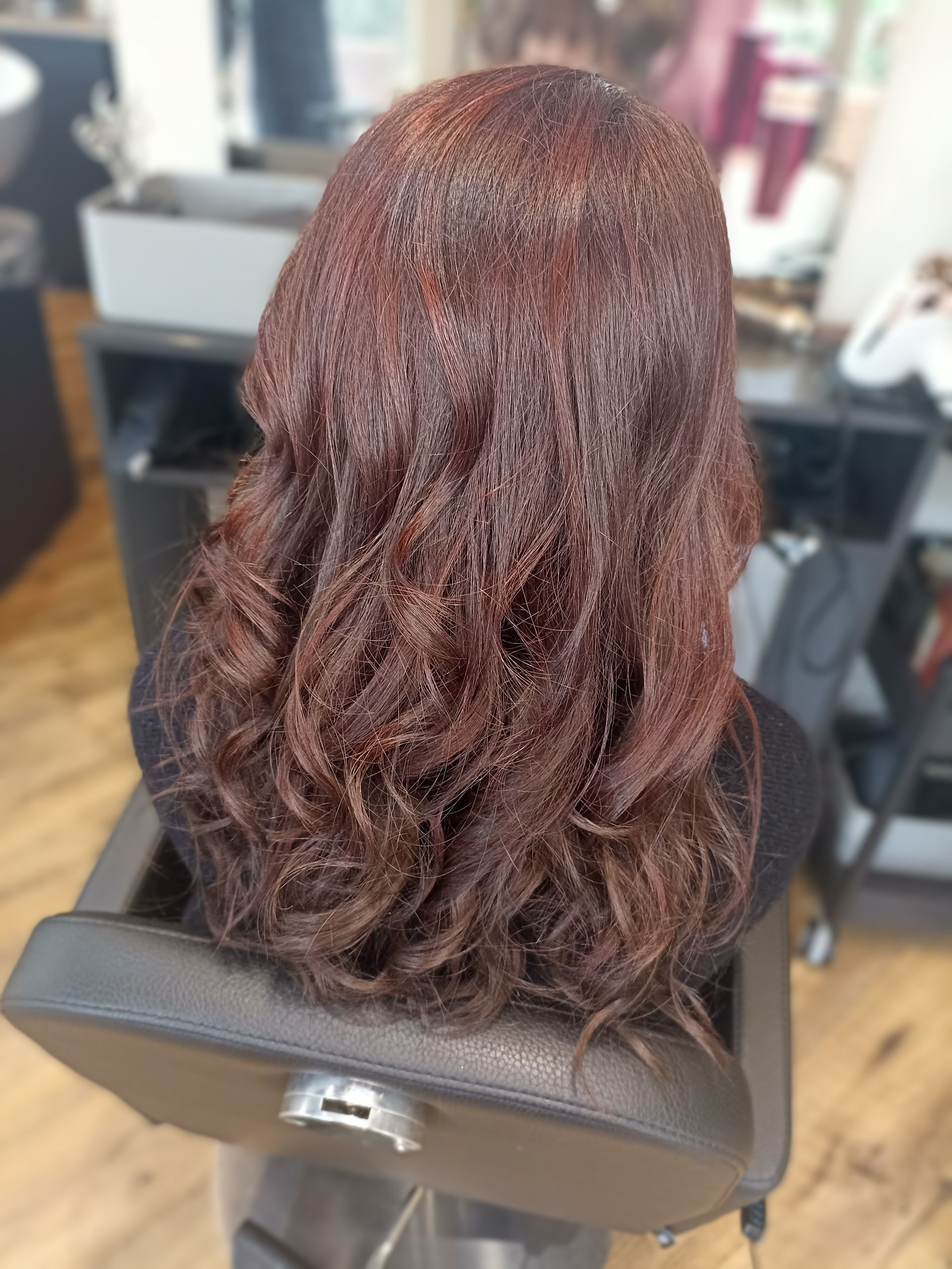 Une femme est assise sur une chaise avec ses cheveux dans un salon.