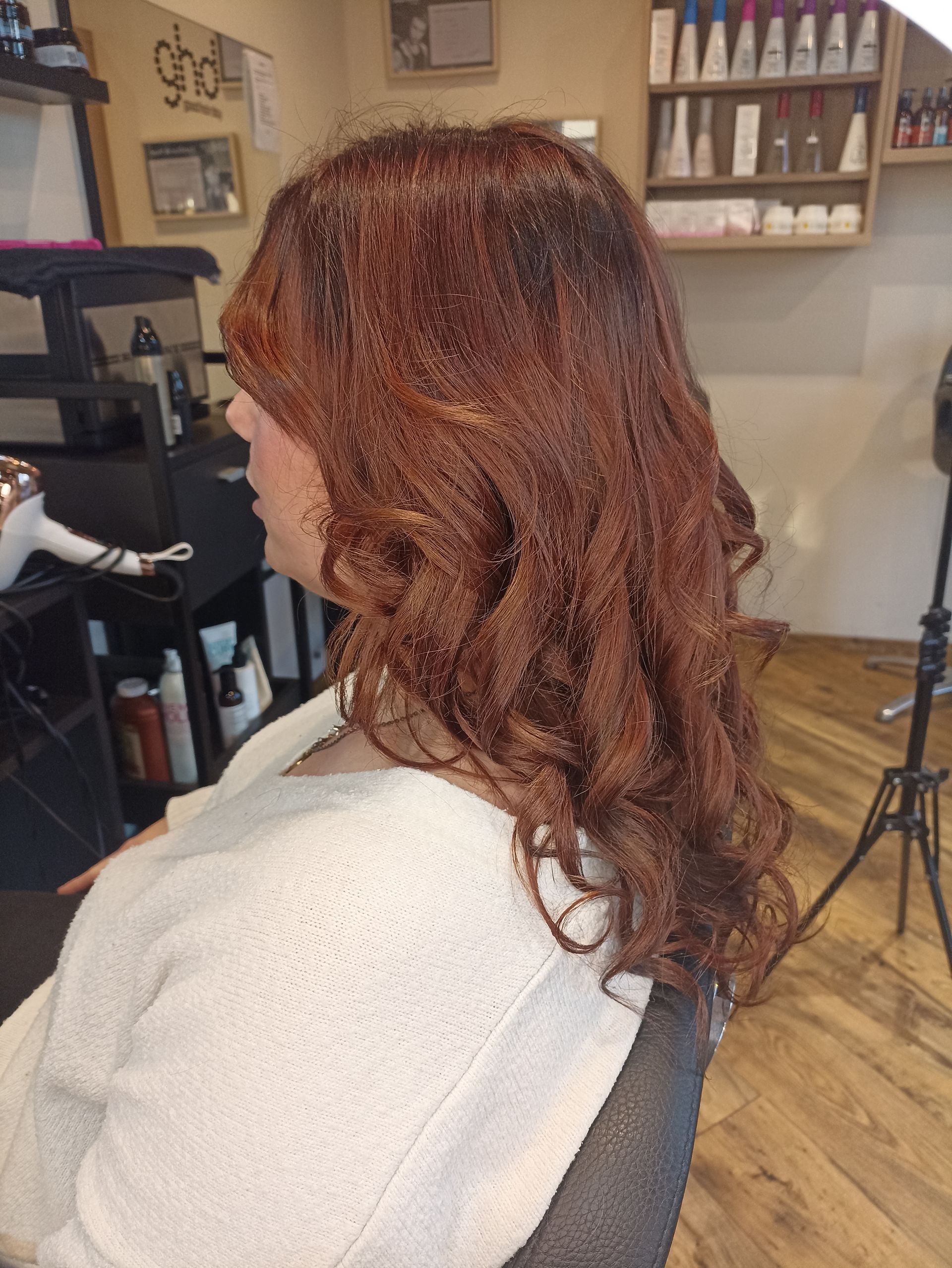 Une femme aux cheveux roux est assise sur une chaise dans un salon