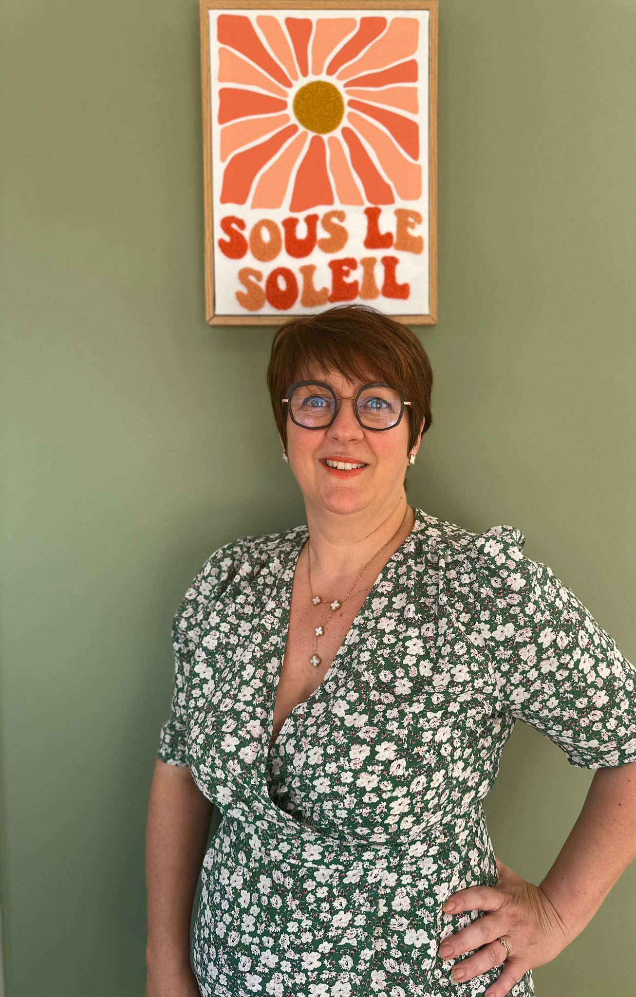 Une femme portant des lunettes et une chemise noire sourit à la caméra.