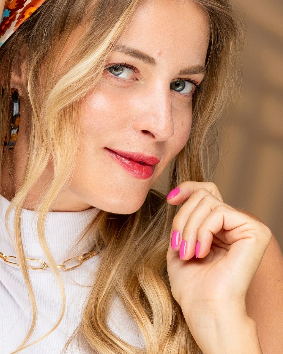 Un gros plan du visage d'une femme avec des ongles roses et un foulard autour de la tête.