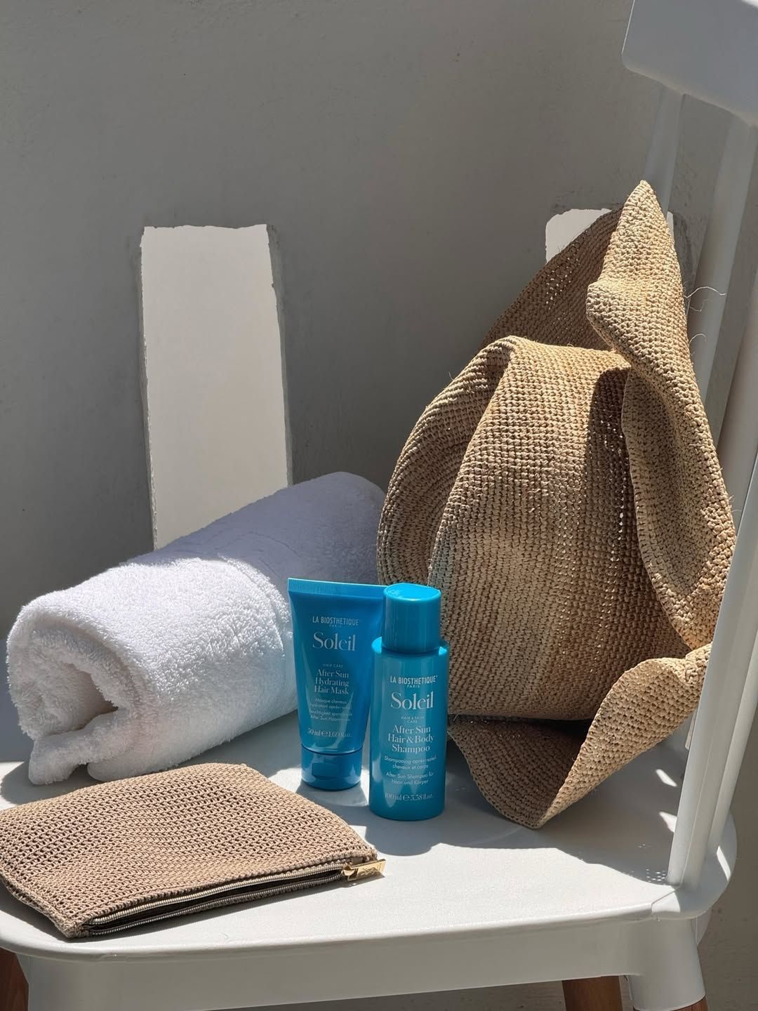 Un chapeau de paille est posé sur une chaise à côté d'une serviette et de deux bouteilles de lotion.