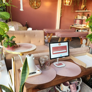 Cozy café table with iMac, mugs, vase, and pink decor in a warm lounge interior