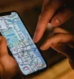 Hands pointing at a phone screen displaying a city map.