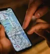 Hands pointing at a phone screen displaying a city map.