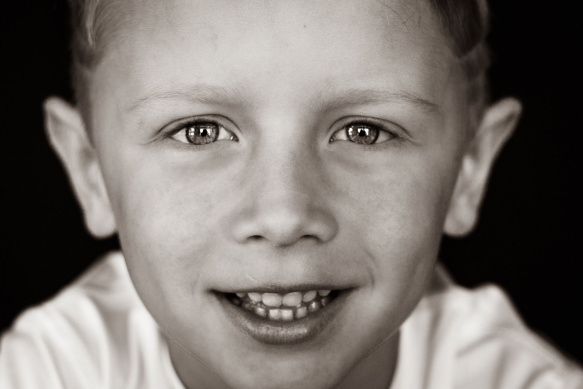 A young boy is smiling in a black and white photo.