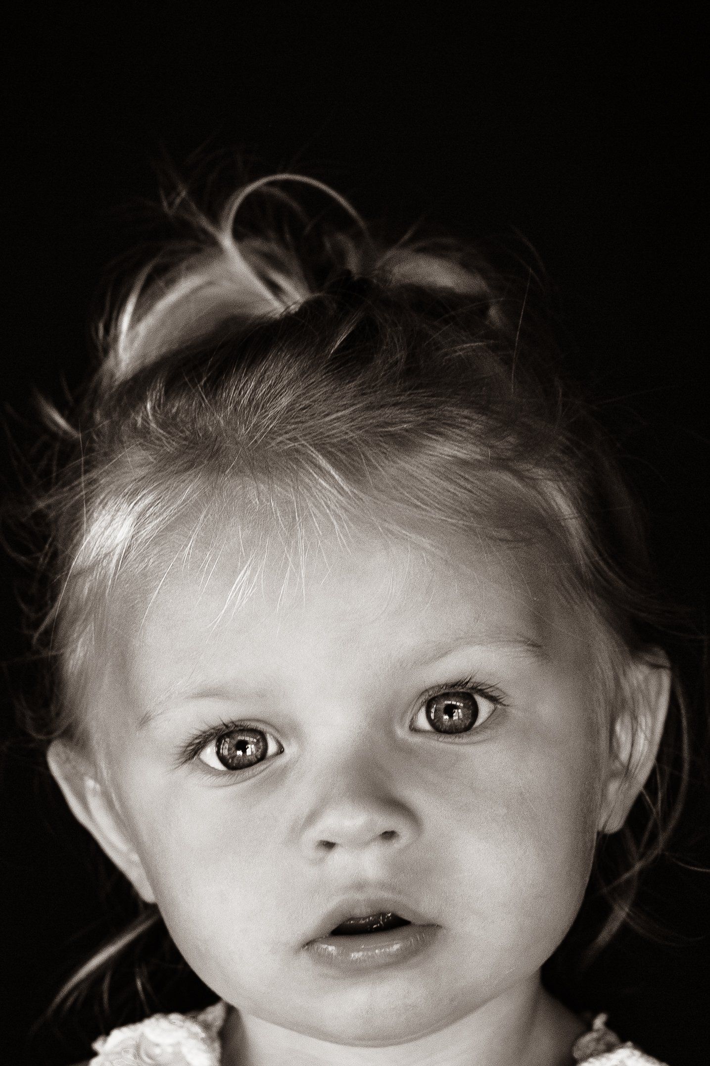 A black and white photo of a little girl with a surprised look on her face.
