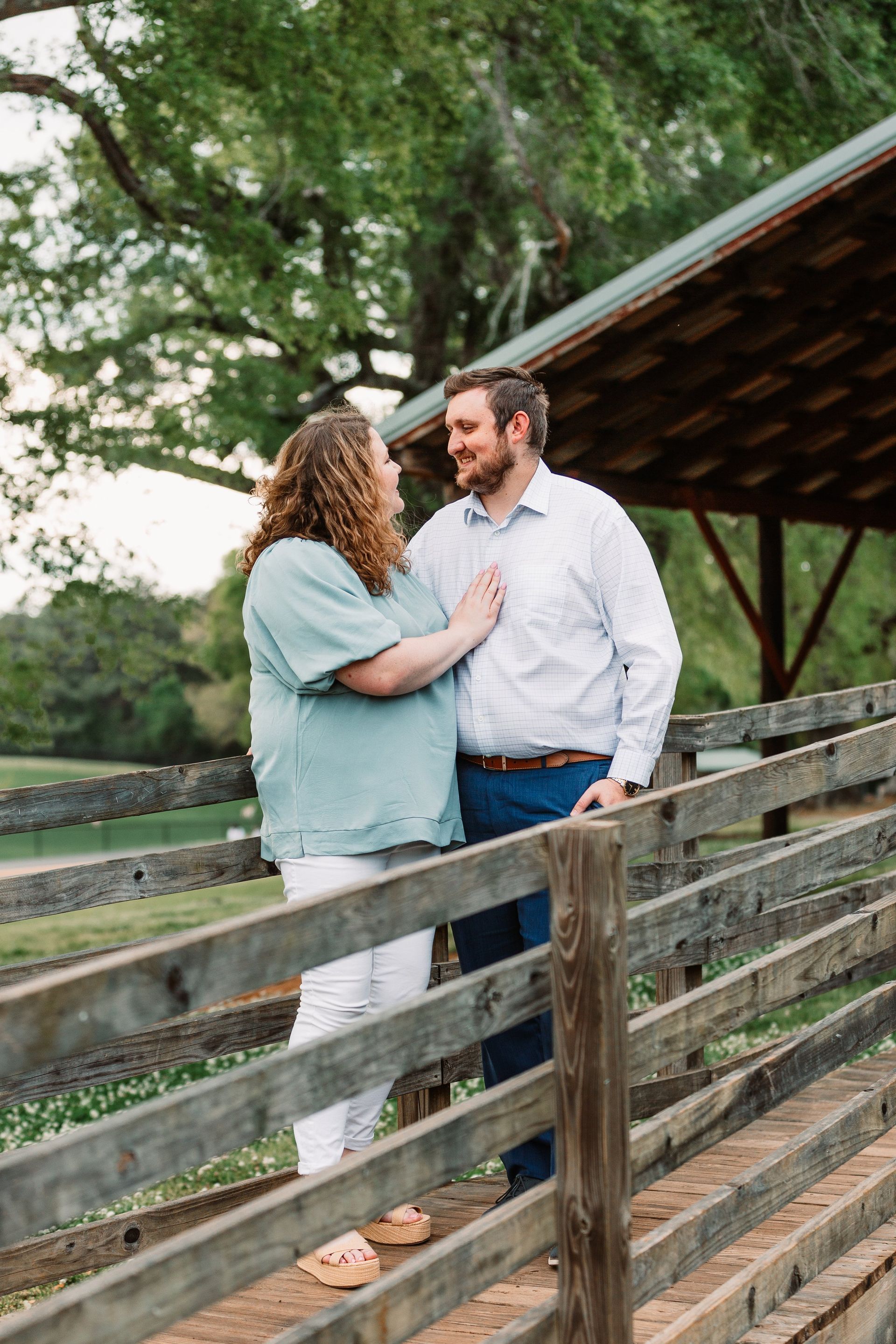 A man and a woman are standing next to a wooden fence.