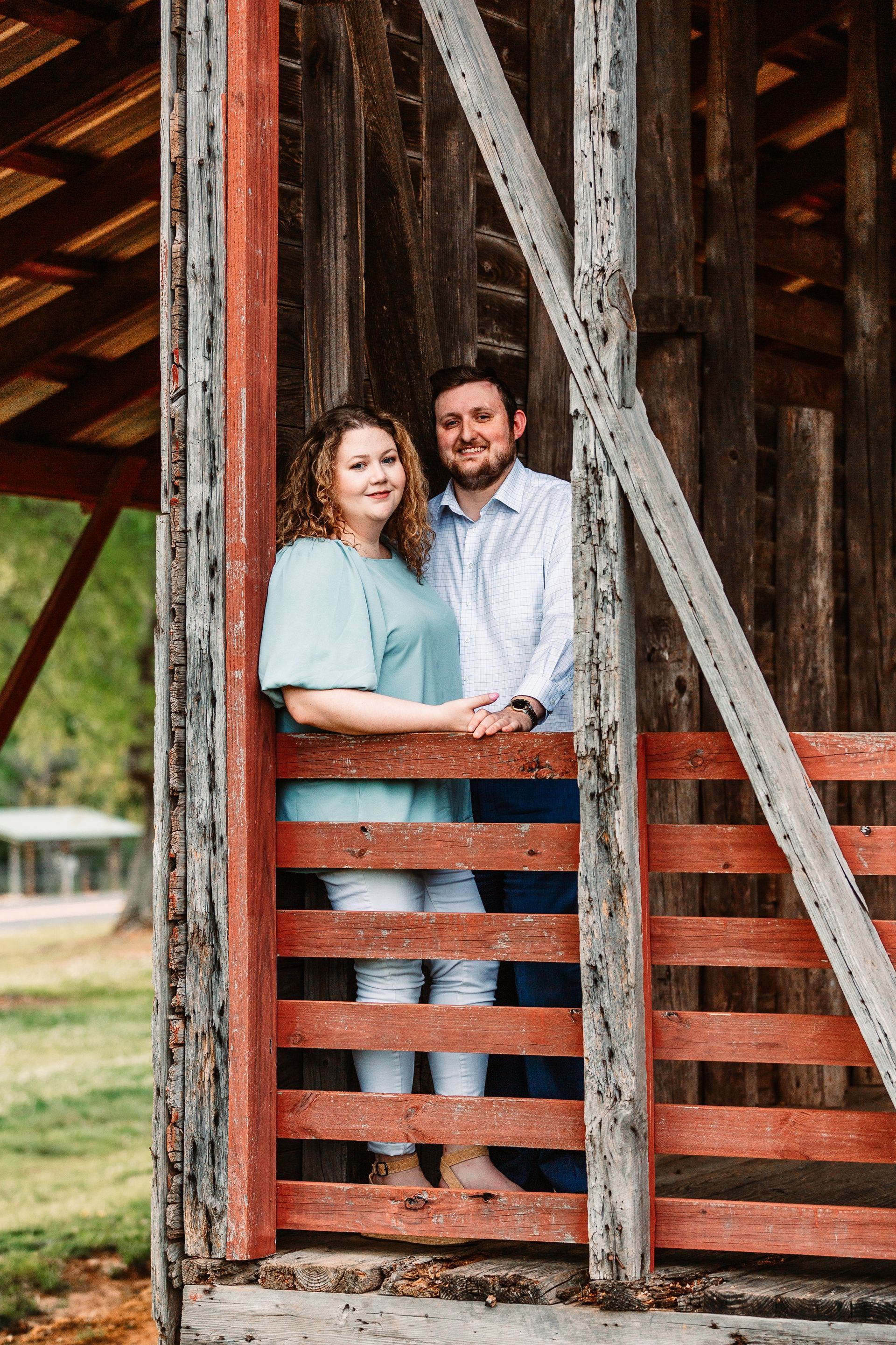 A man and a woman are standing next to each other behind a red fence.