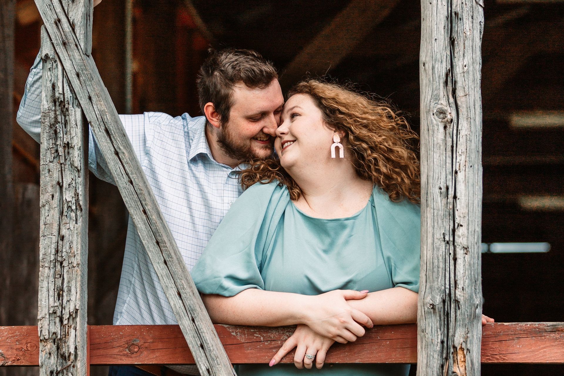 A man and a woman are standing next to each other on a wooden fence.