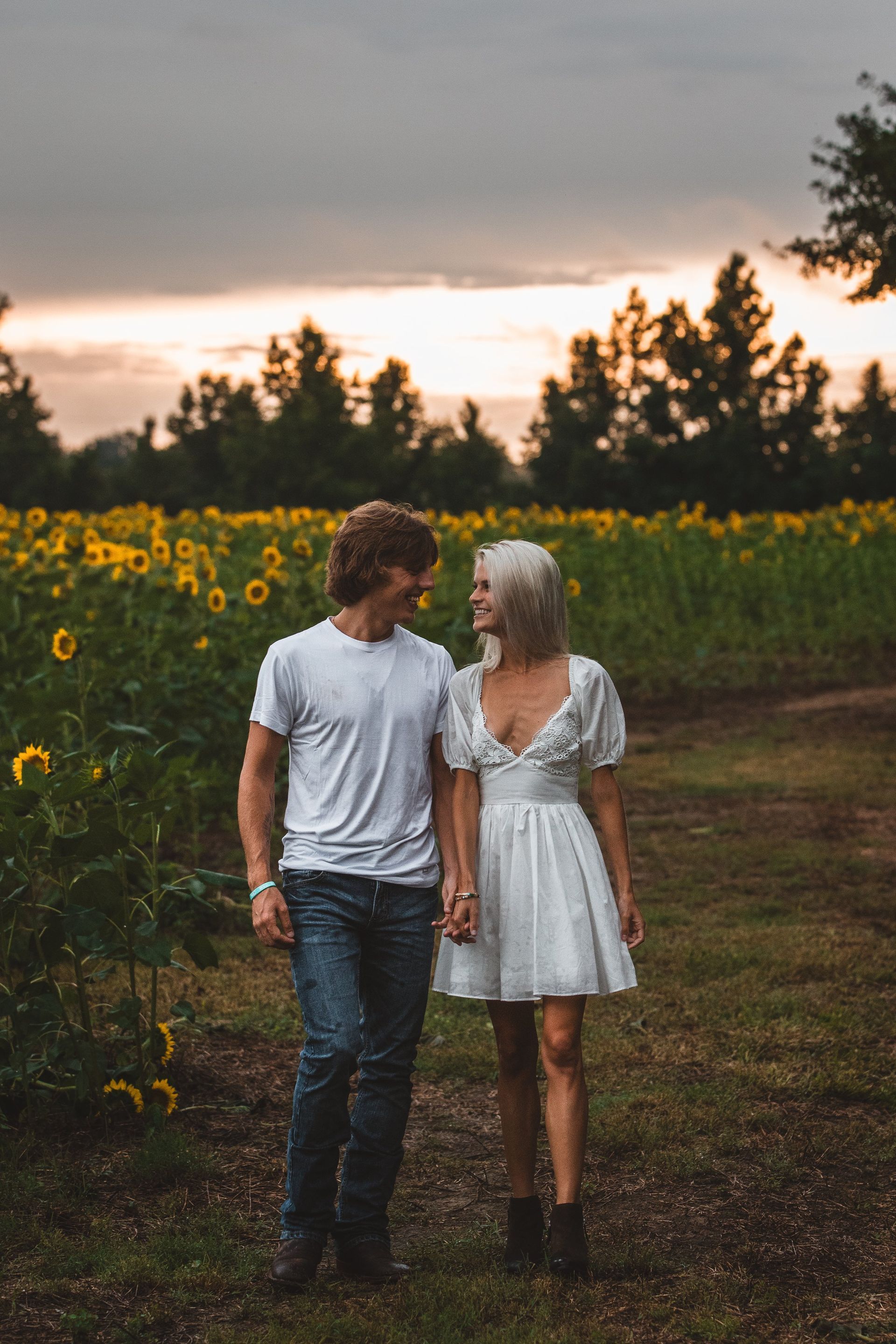 A man and a woman are walking through a field of sunflowers.