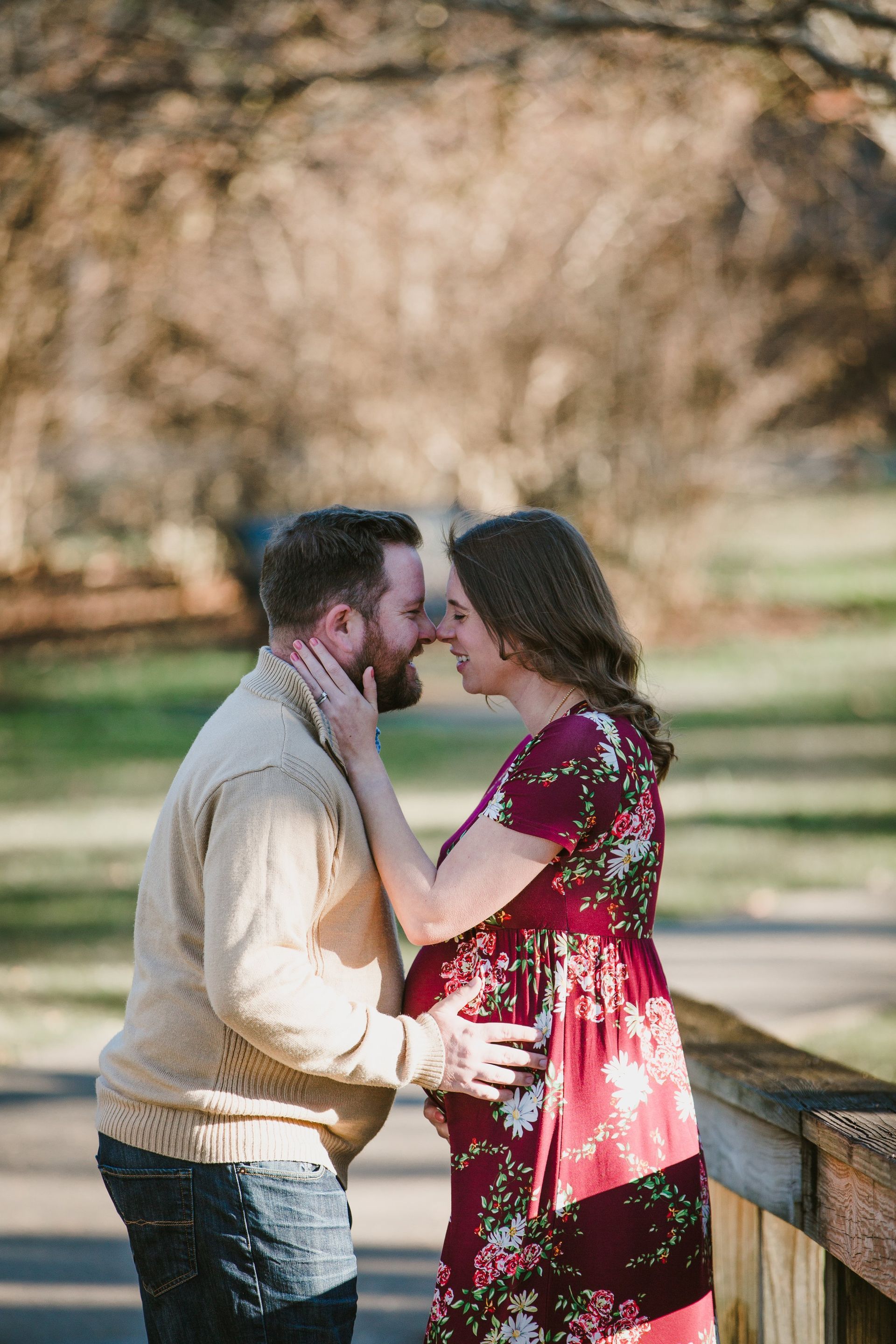 A man and a pregnant woman are kissing in a park.