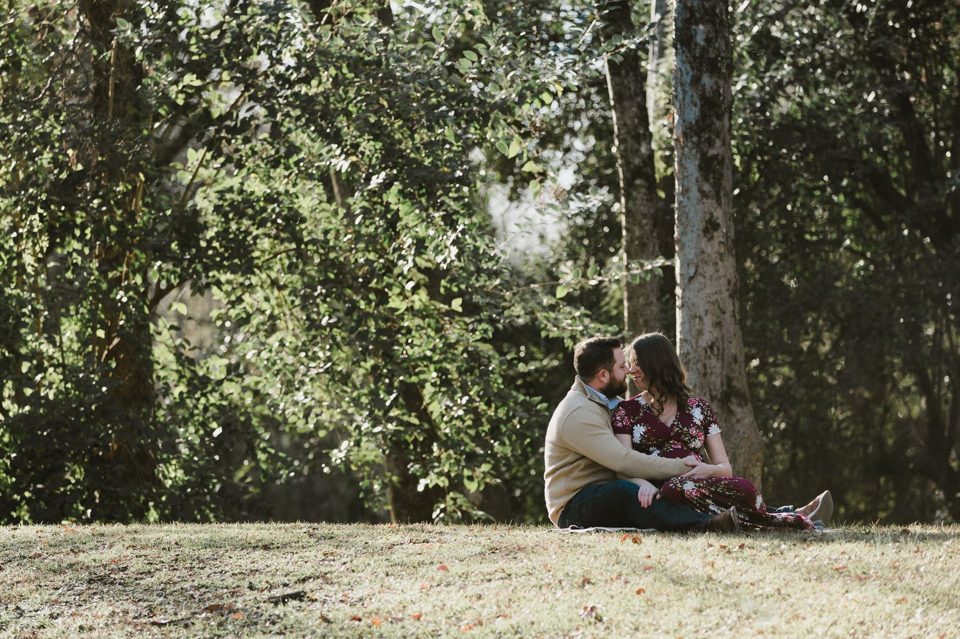 A man and a woman are sitting under a tree in a park.