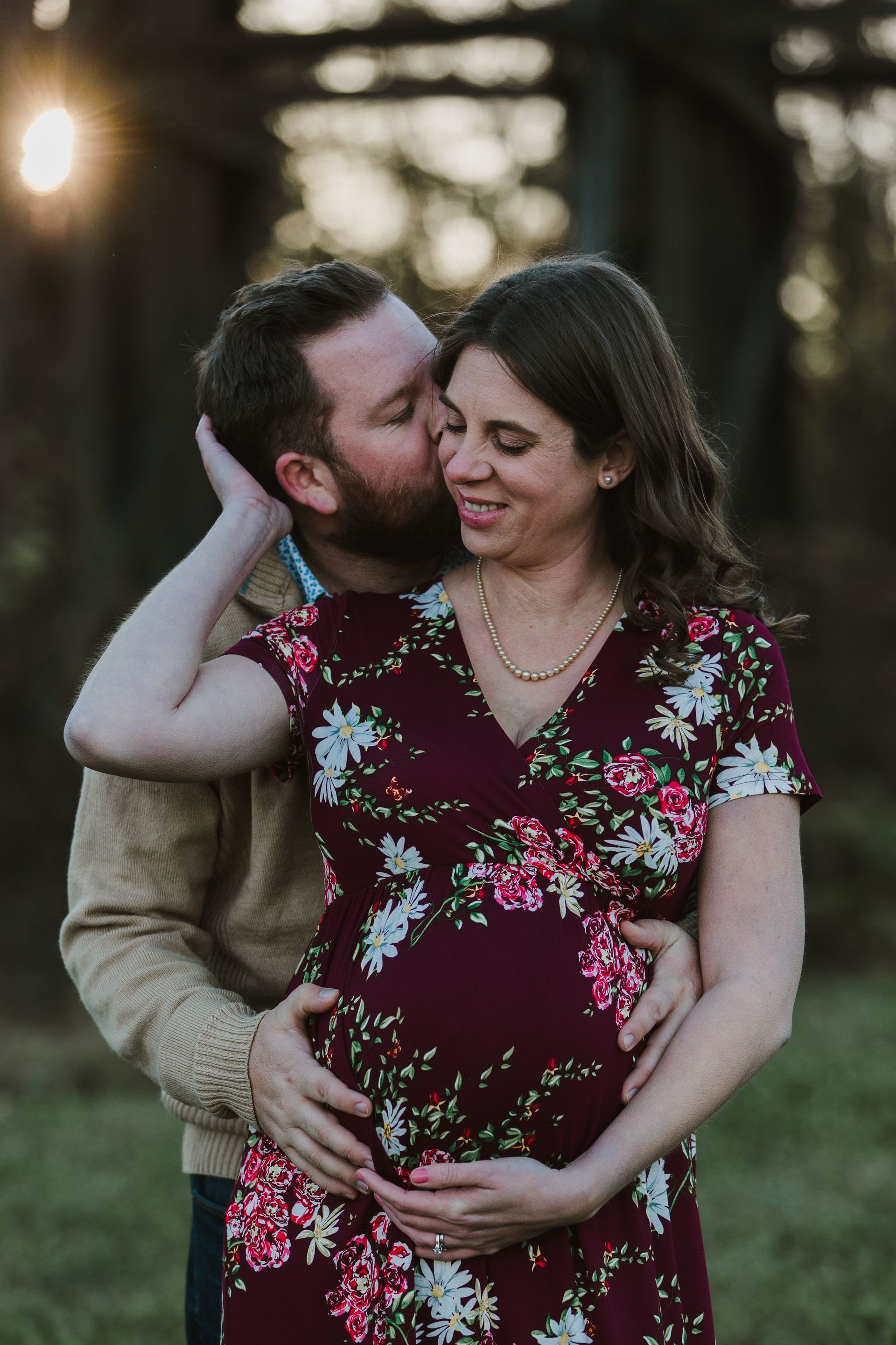 A man is kissing a pregnant woman on the cheek.