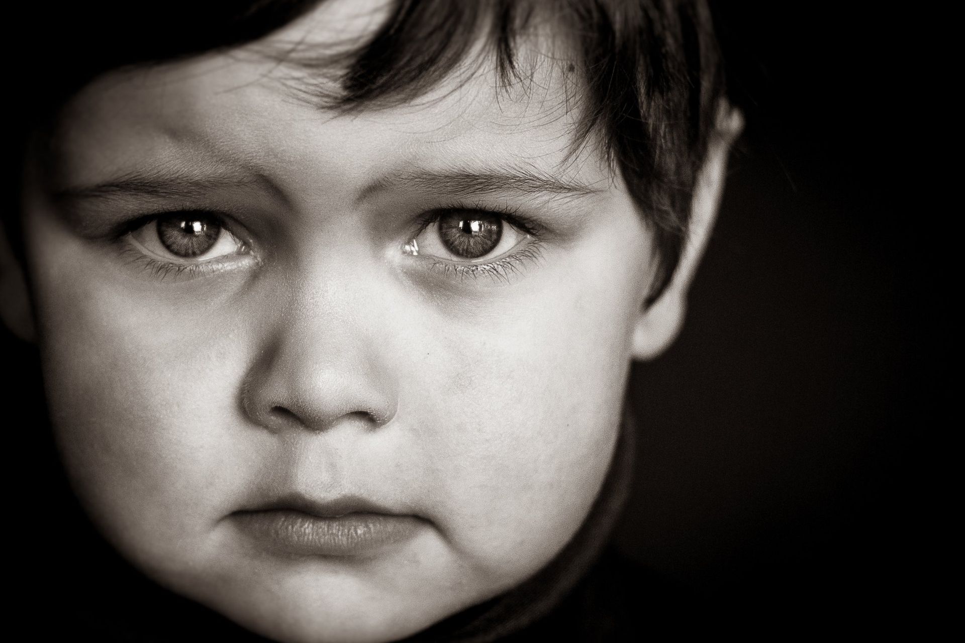 A black and white photo of a young boy with a sad look on his face.