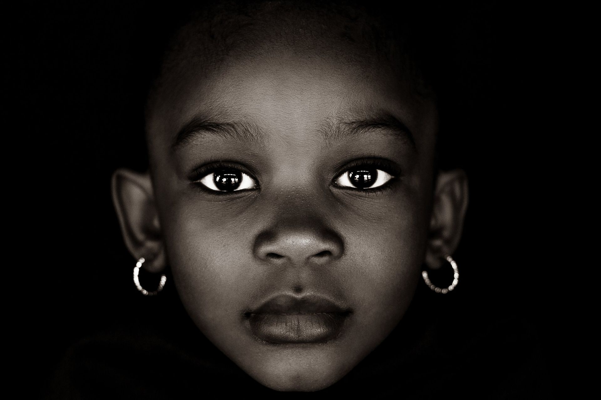 A close up of a child 's face with hoop earrings