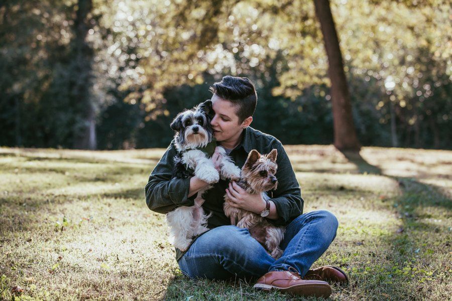 A man is sitting on the grass with two dogs.