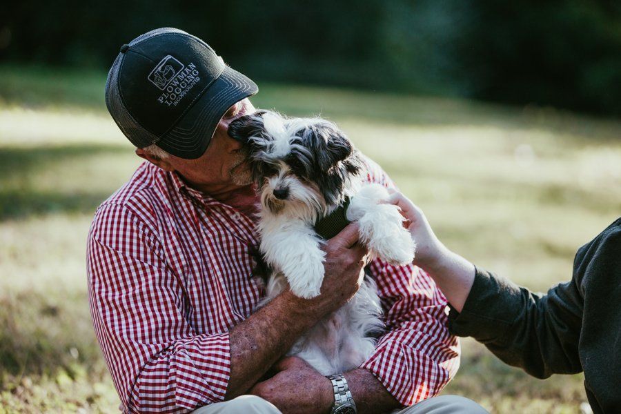 A man is holding a small dog in his arms.