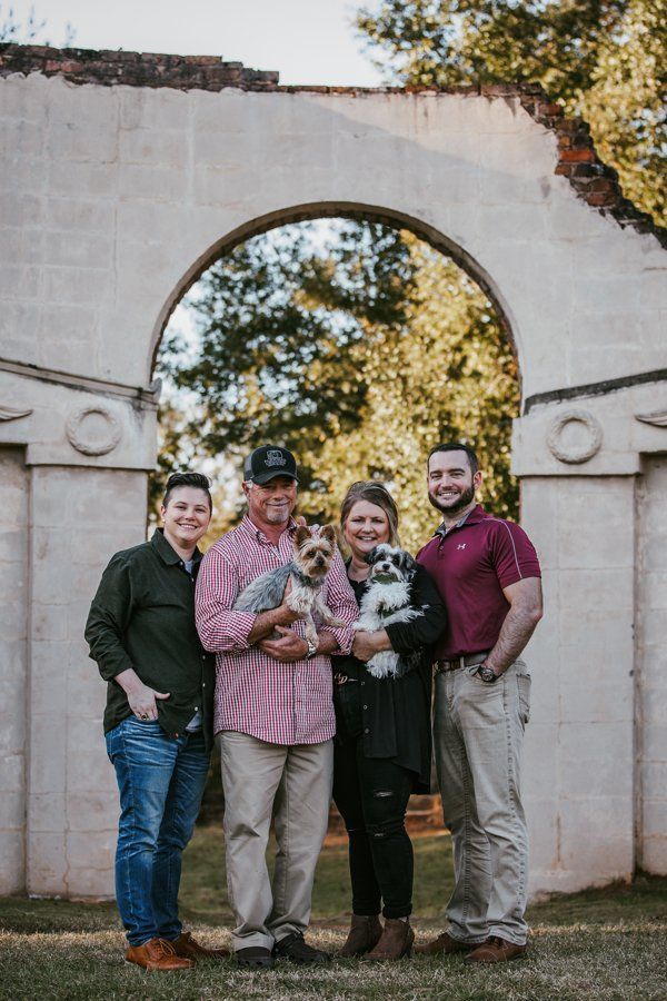 A family is posing for a picture with their dog.