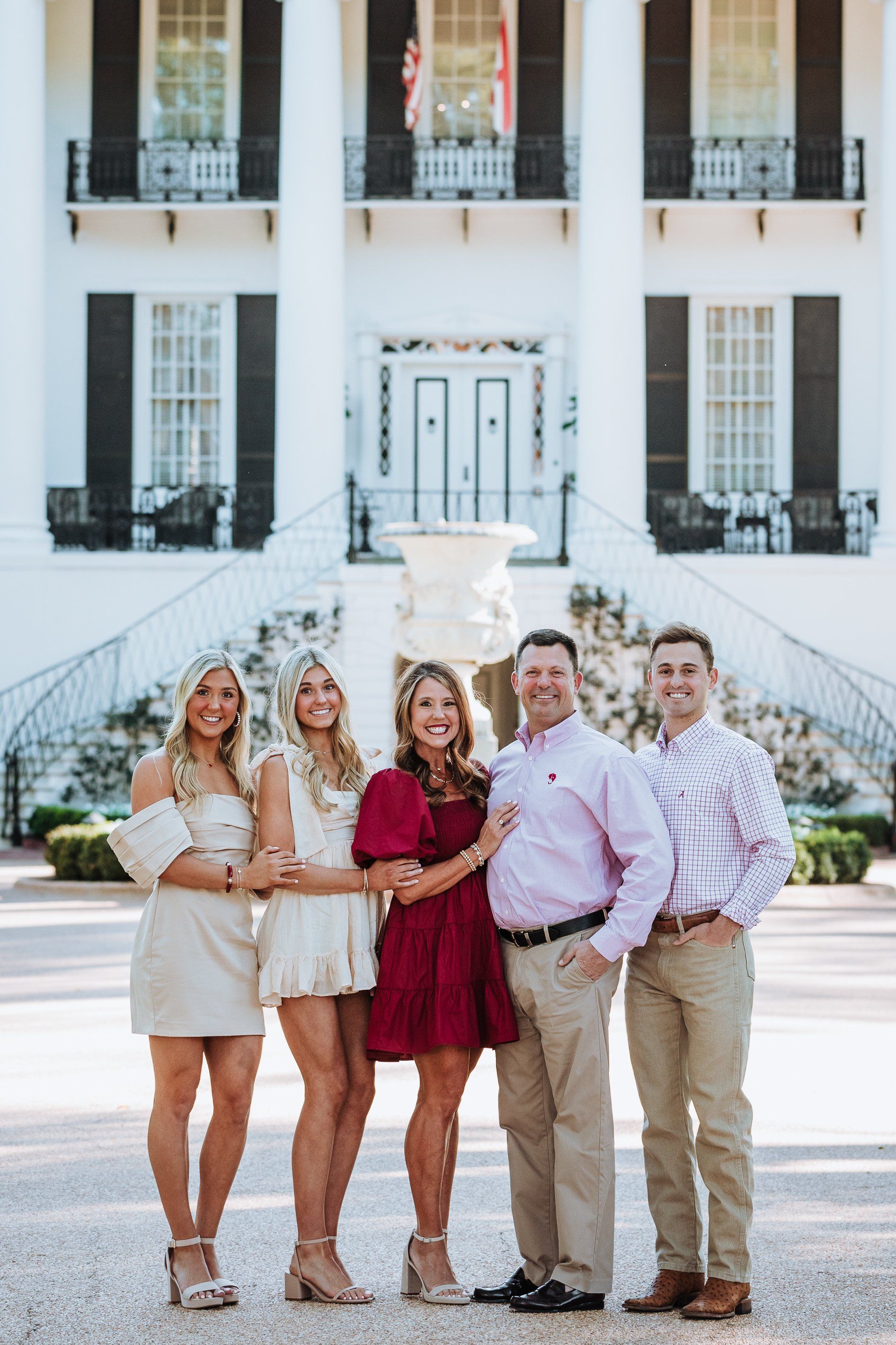 A group of people are posing for a picture in front of a large white building.