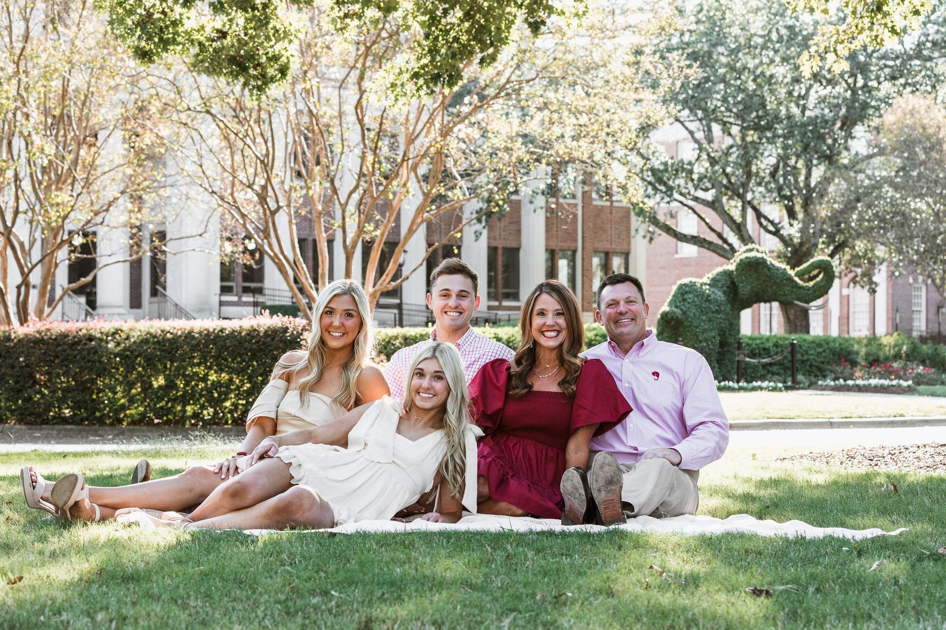A group of people are sitting on a blanket in the grass.