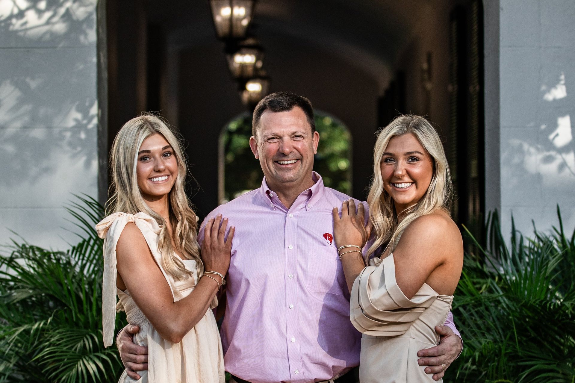 A man and two women are posing for a picture in front of a house.