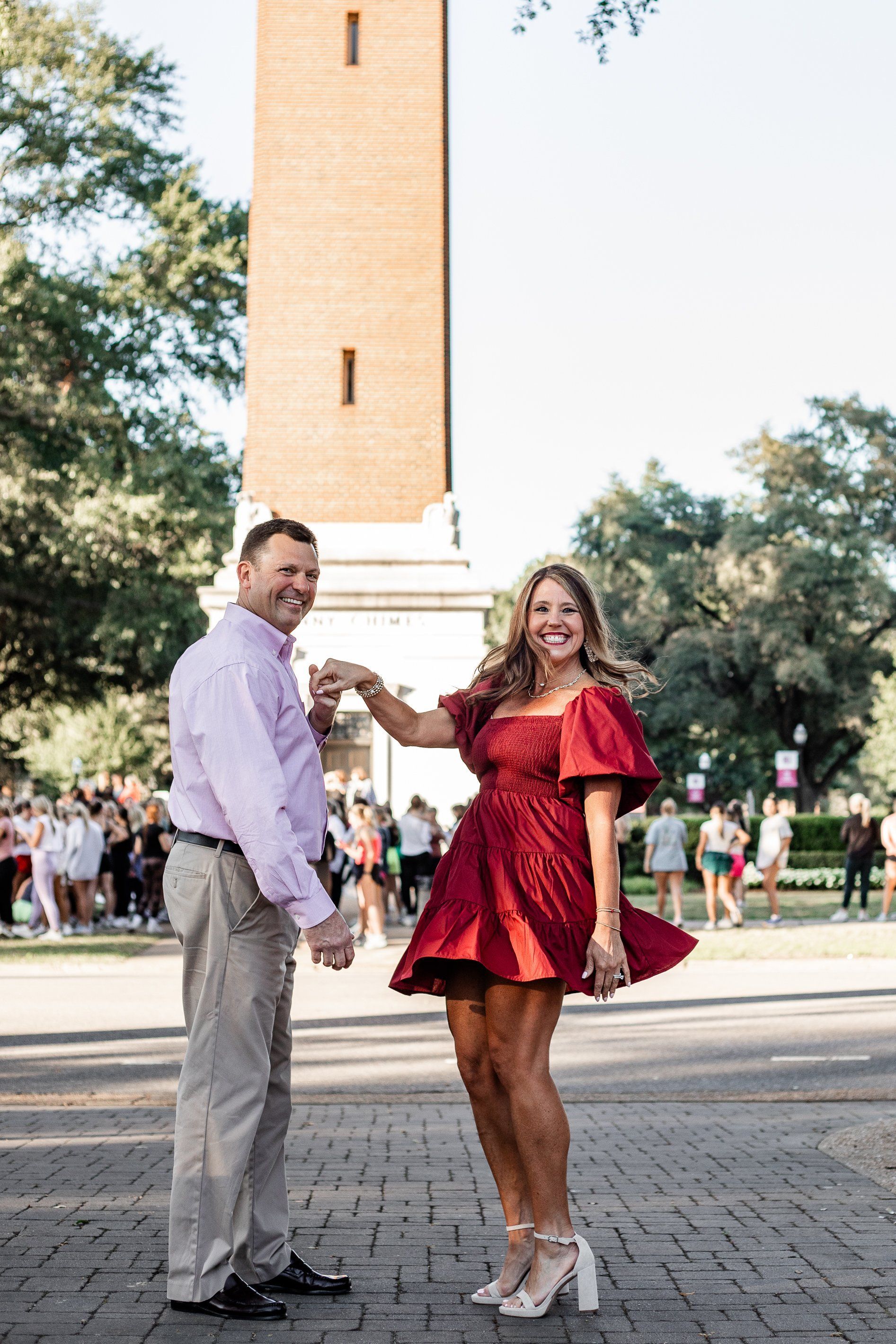A man and a woman are dancing in front of a clock tower.